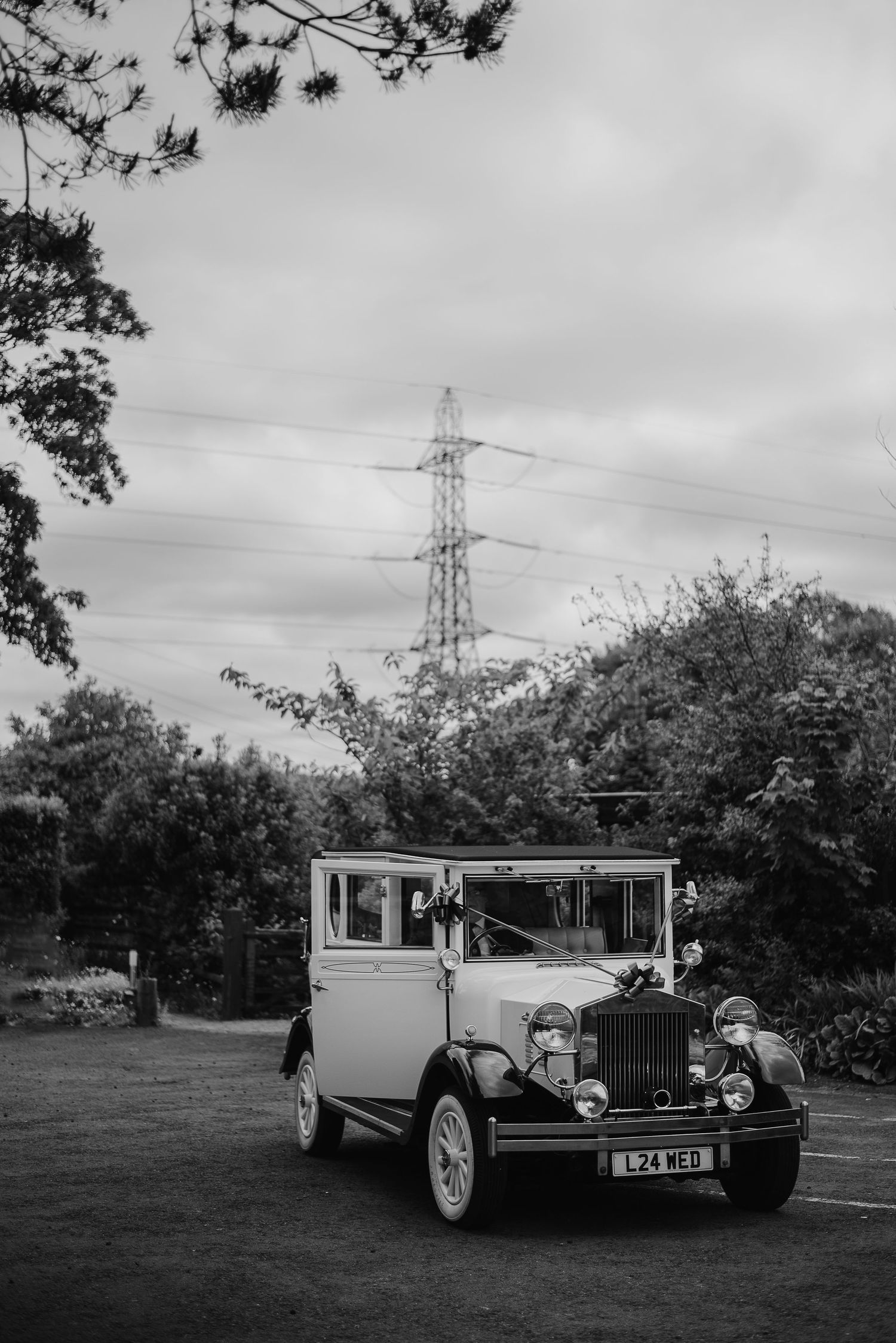 A vintage white wedding car parked with power lines visible in the background.