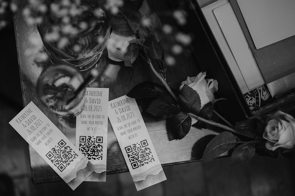 Black and white photo of QR codes and paper materials scattered on a reflective surface.