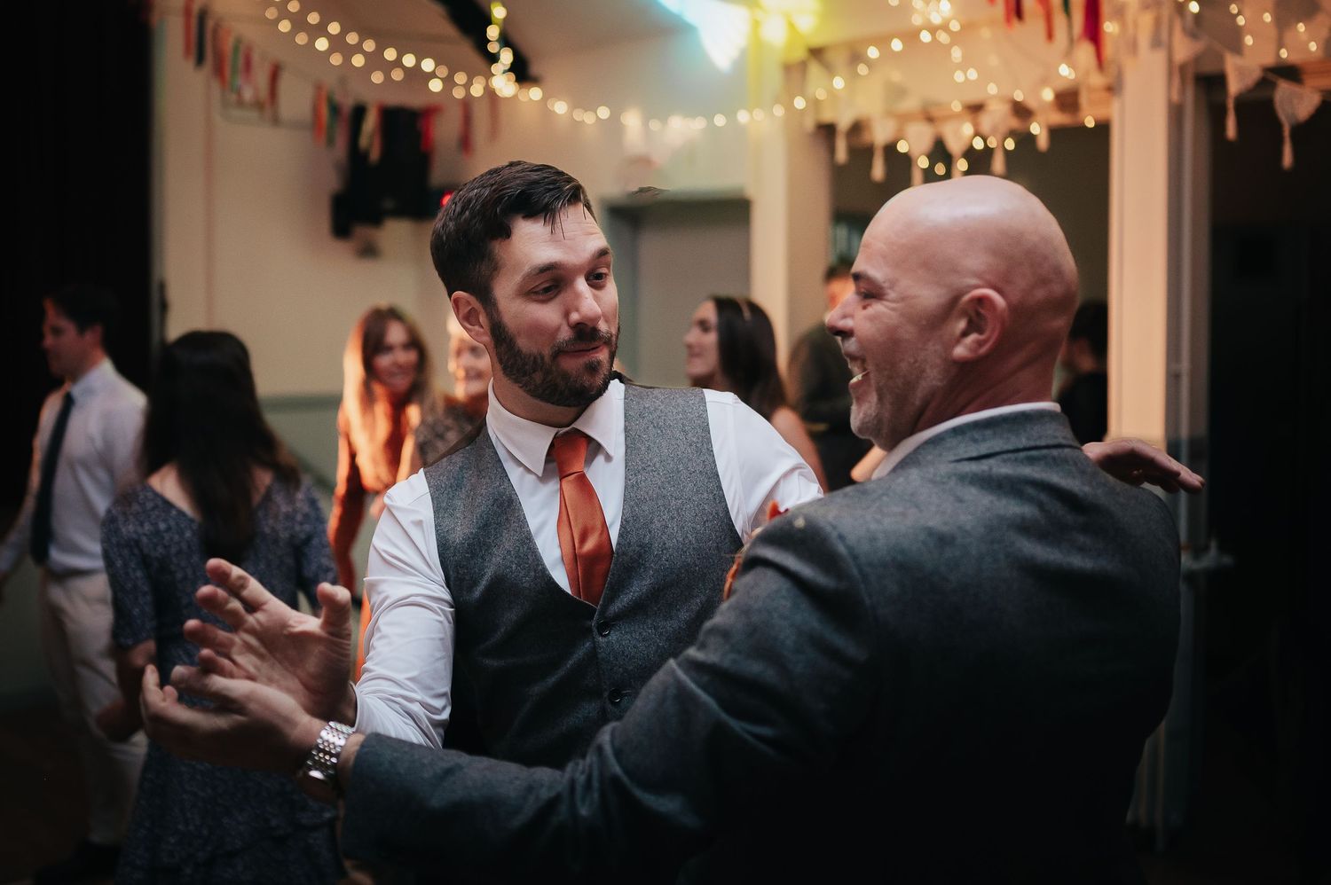 Two guests engaged in animated conversation during evening wedding reception.