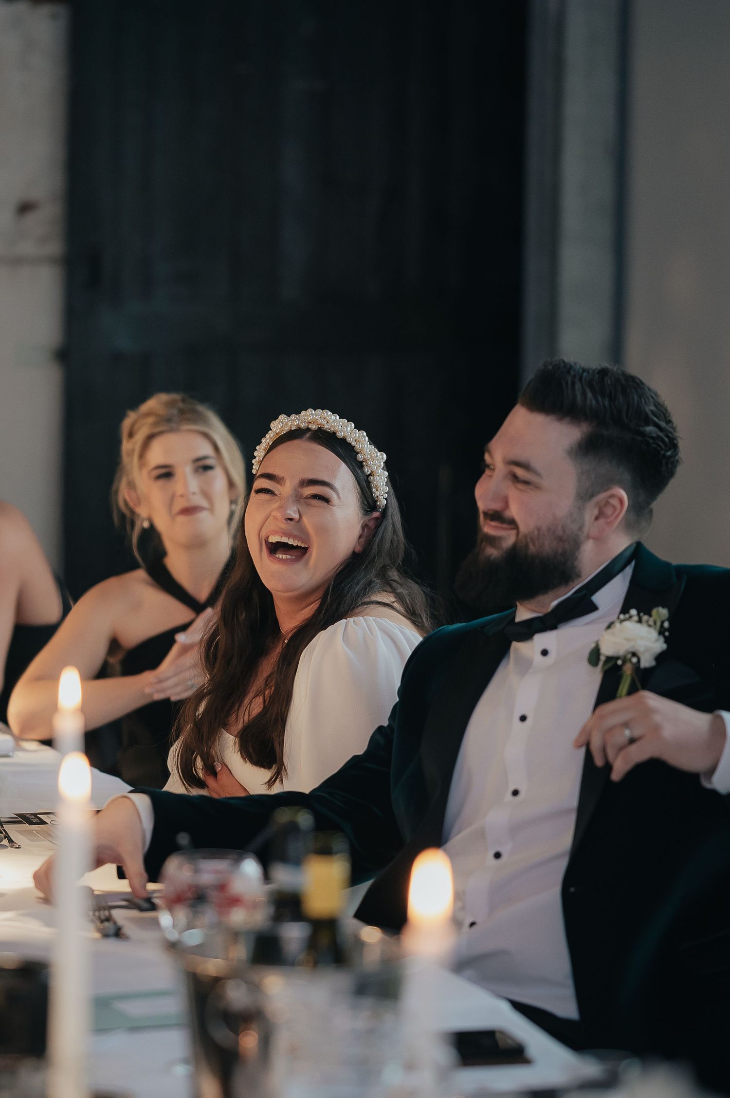 Candlelit wedding reception table with guests sharing a joyful moment.