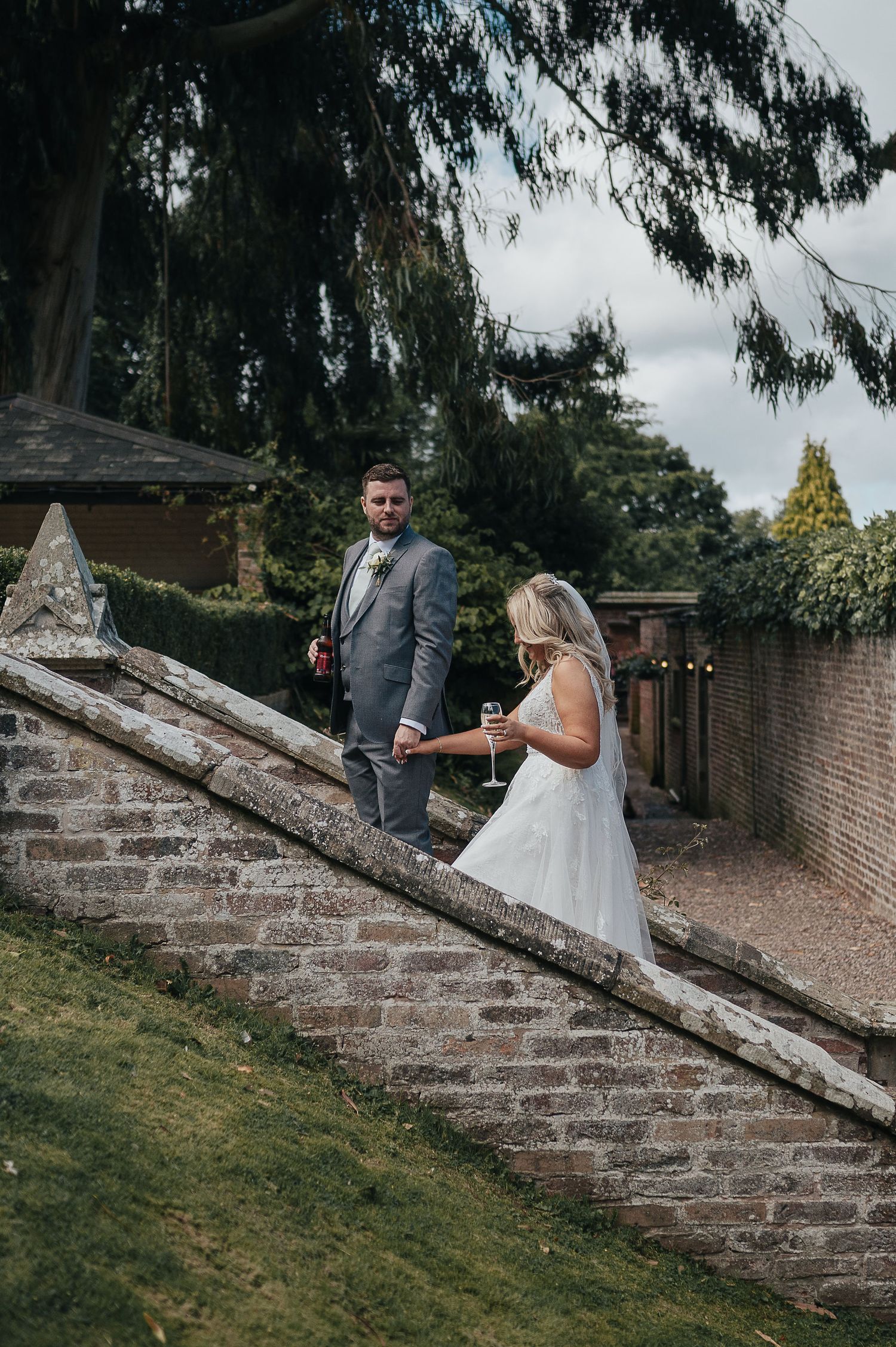 Bride and groom descending brick garden steps during wedding photoshoot.
