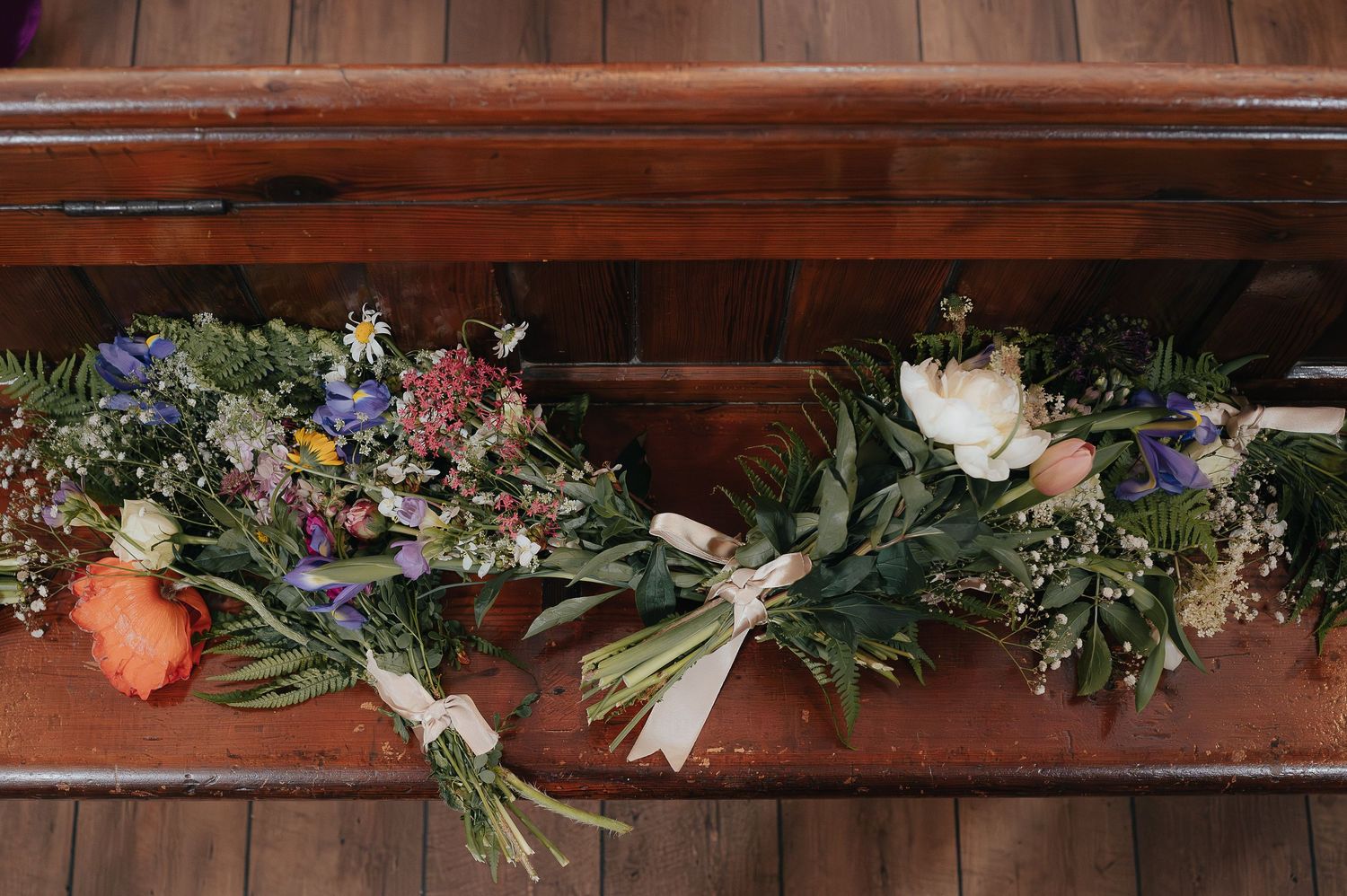 Beautiful wedding bouquets with mixed flowers and greenery arranged on wooden steps.