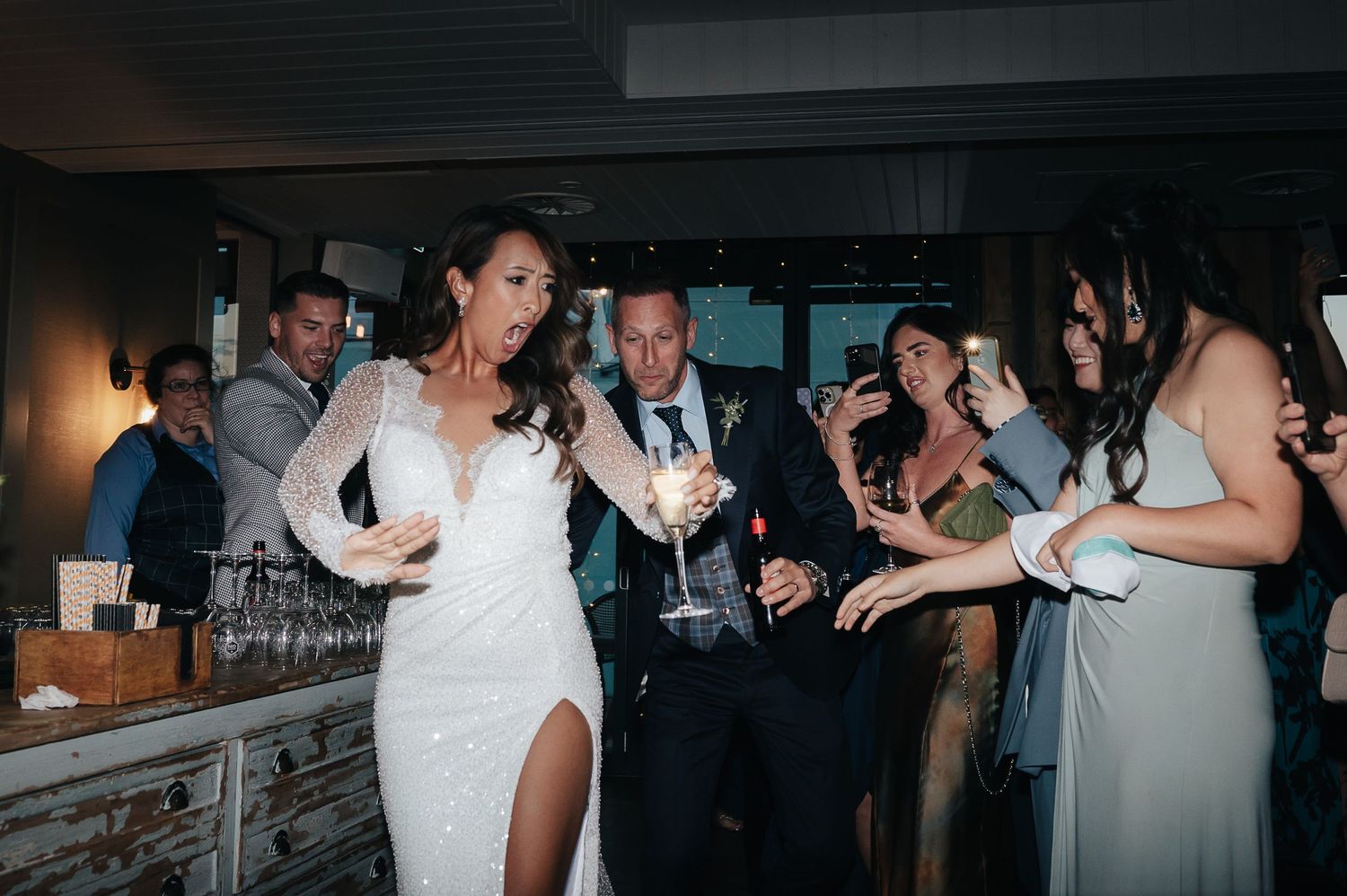 Wedding party dancing and celebrating in an indoor venue filled with joyful energy.