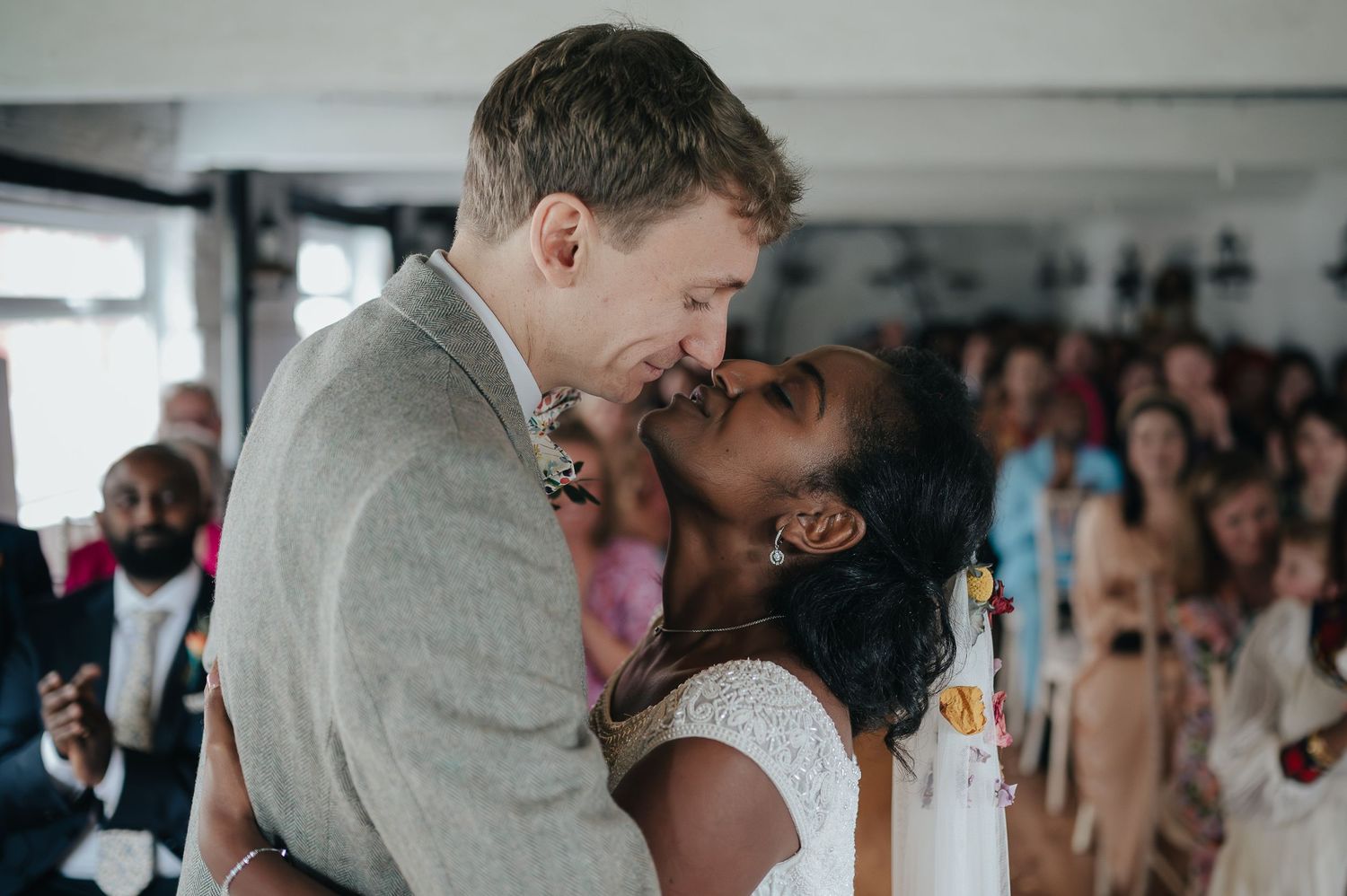 Intimate moment between newlyweds sharing their first kiss at their wedding reception.