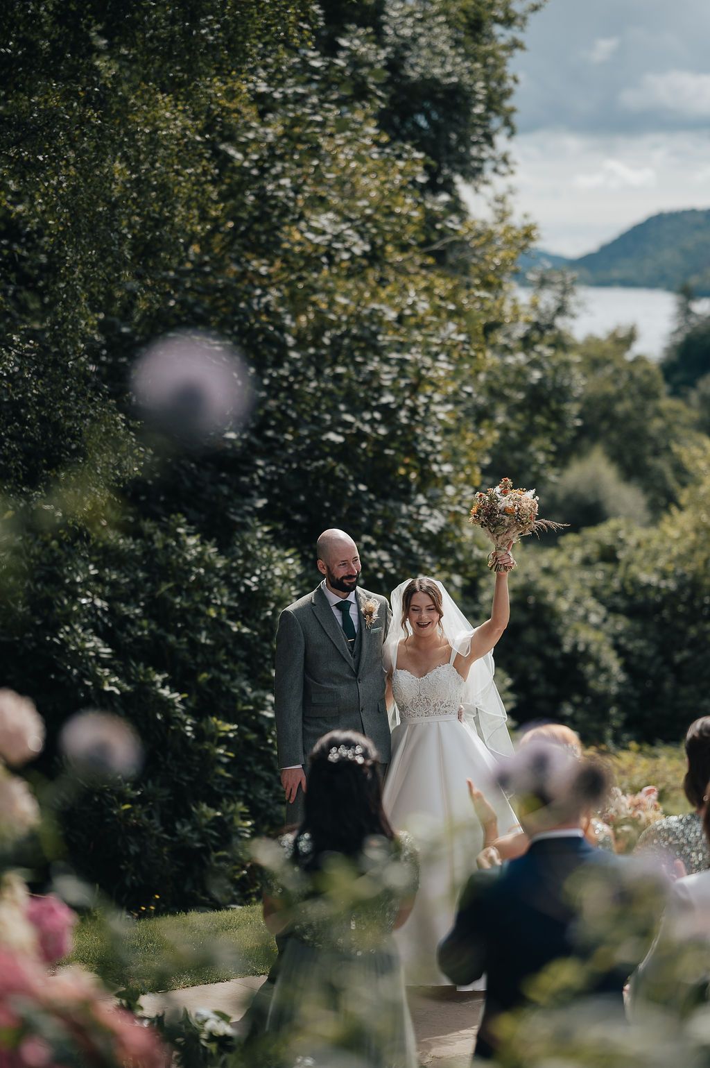 A celebratory wedding moment outdoors with mountain scenery in the background.