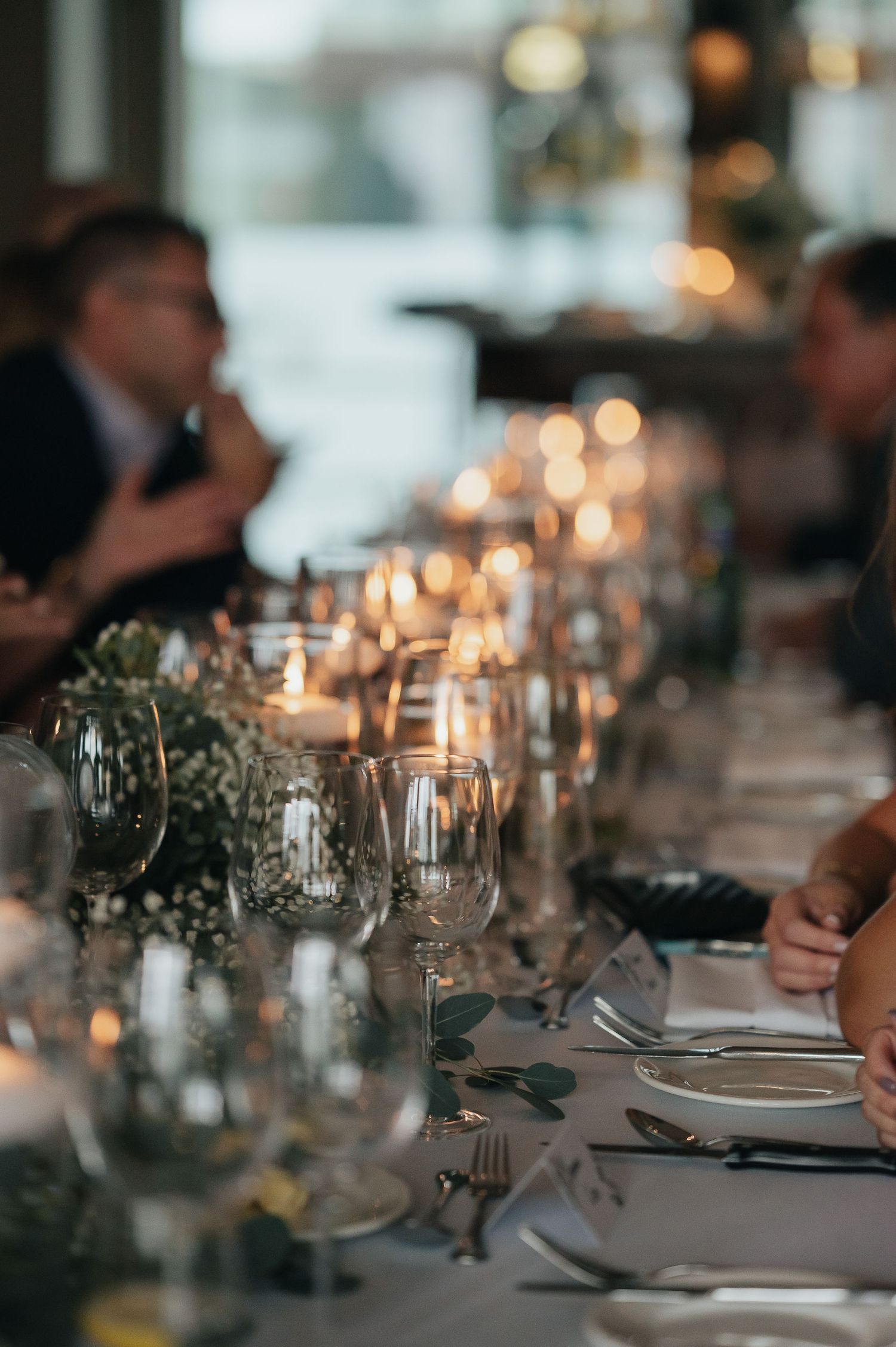 Elegant table setting with candlelight and greenery at a formal dinner event.