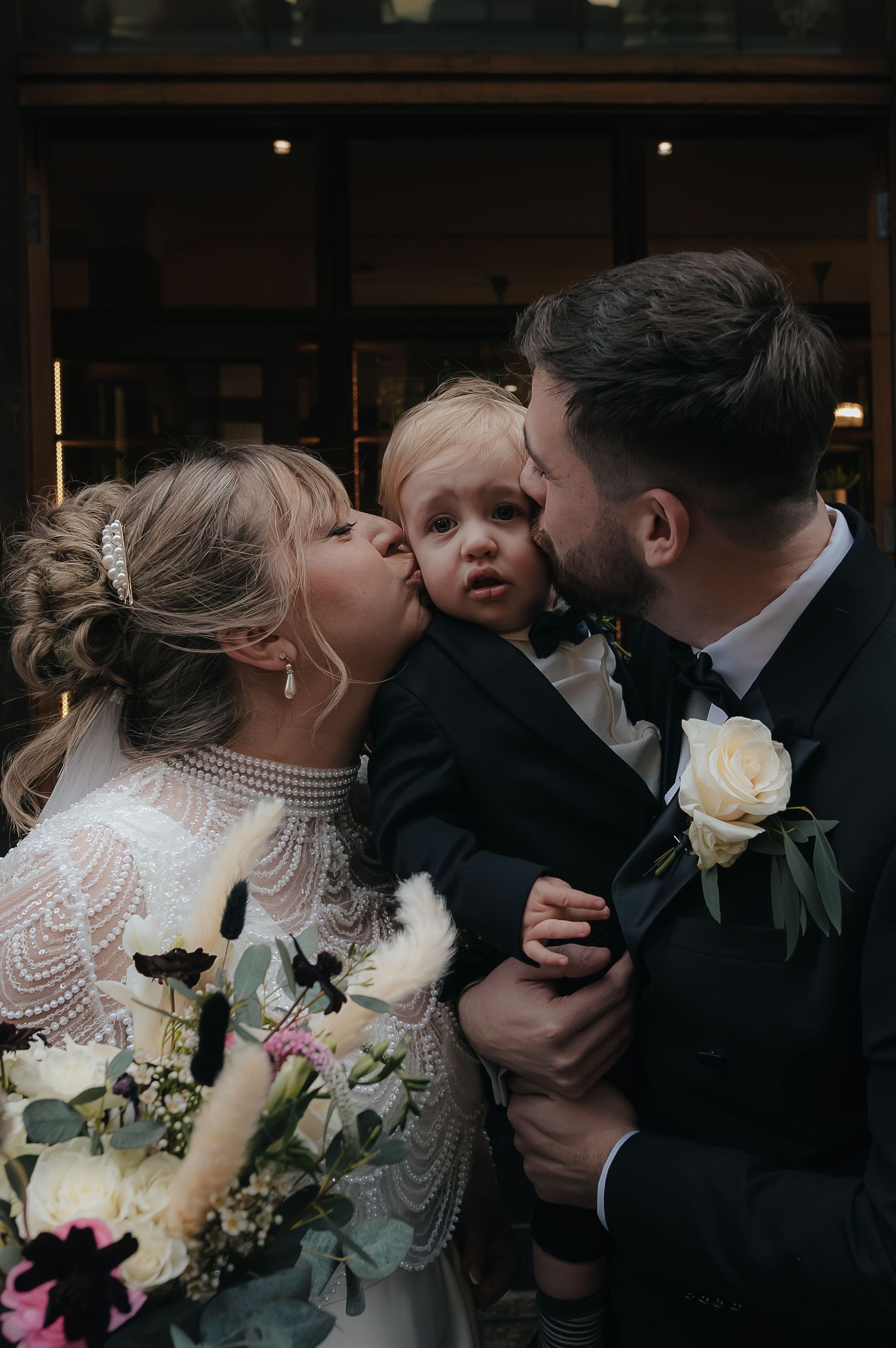 A romantic couple in wedding attire share an intimate dark and moody moment during their celebration.