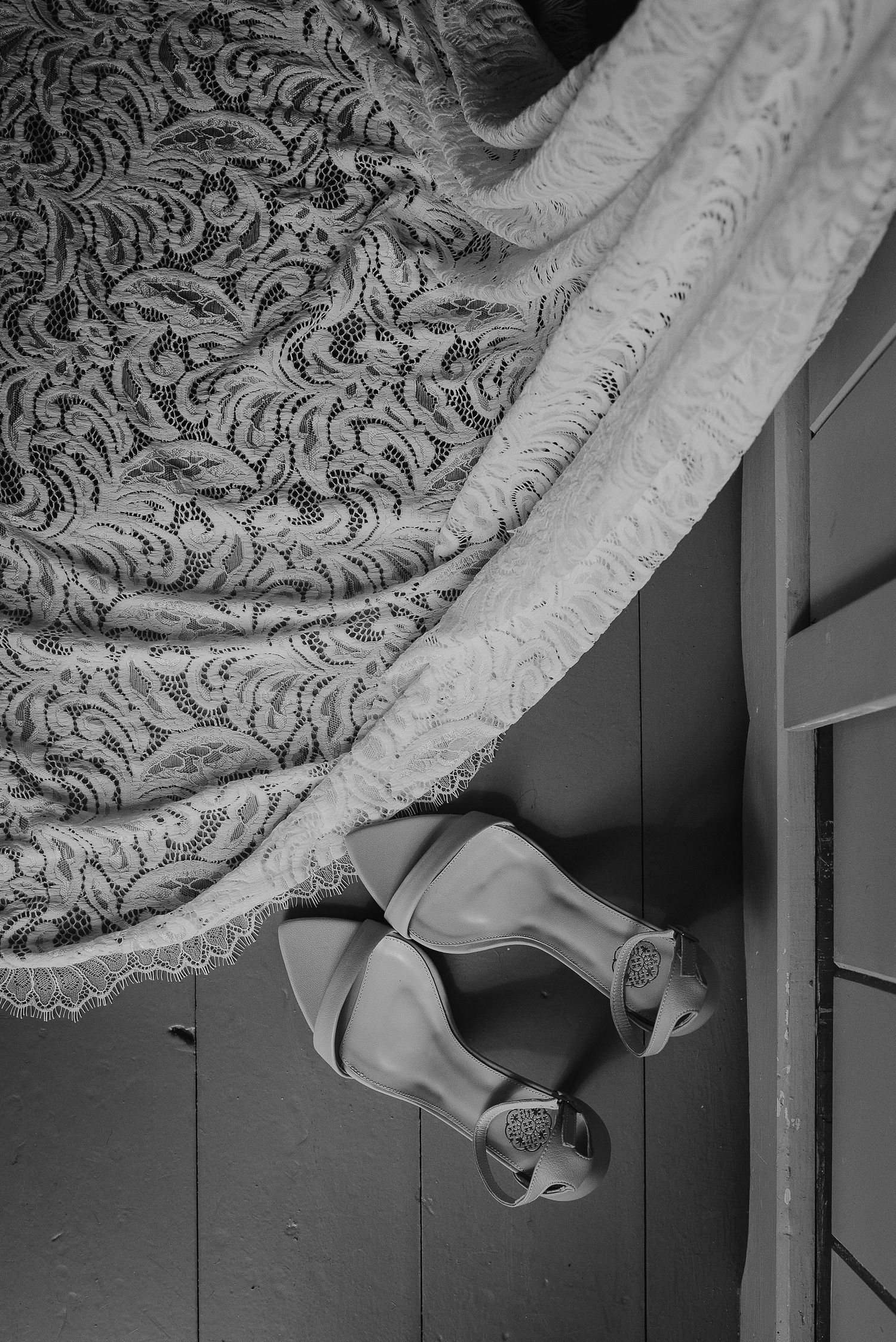 Detail shot of vintage lace wedding dress fabric and elegant heels in black and white.