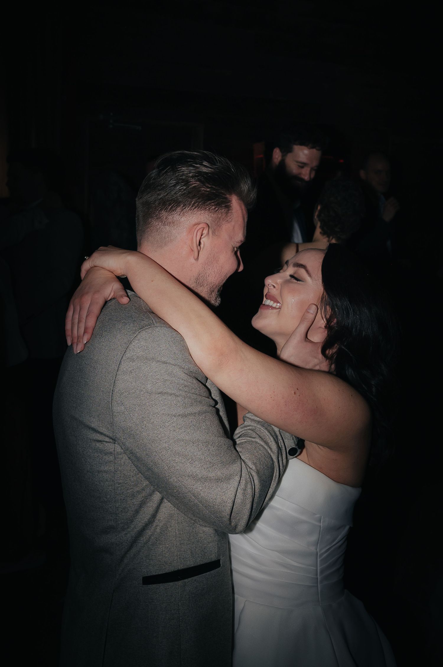 A romantic slow dance moment captured in low light at a wedding reception.