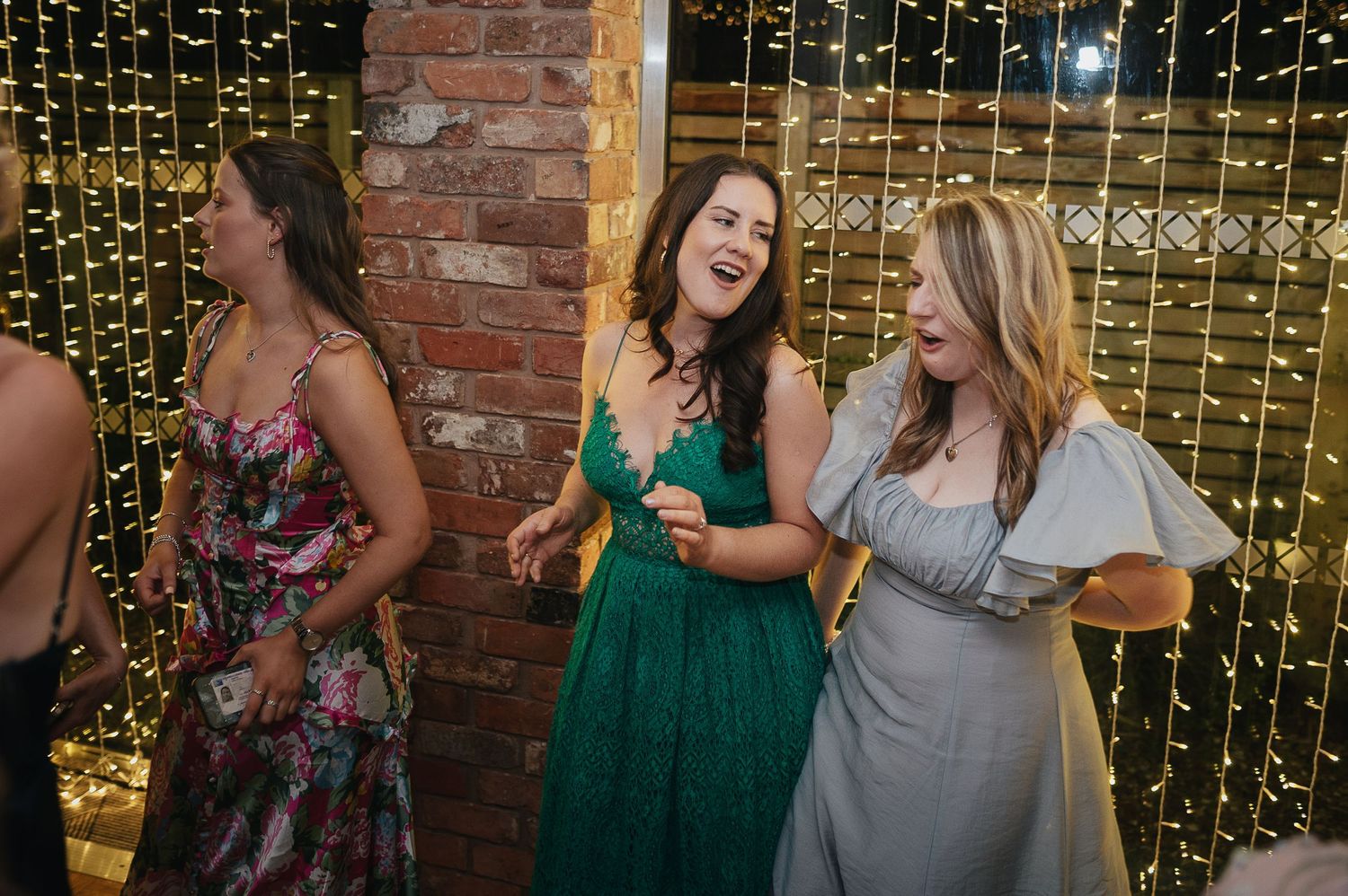Wedding guests enjoying themselves against backdrop of sparkling fairy lights.