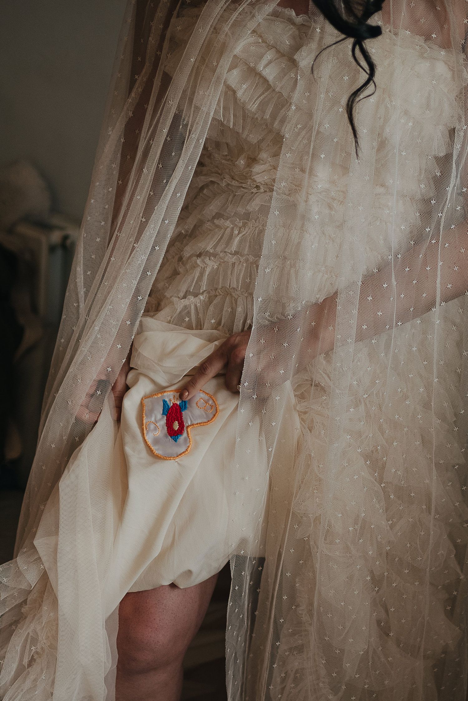 Close-up of embroidered detail through delicate white wedding dress tulle.