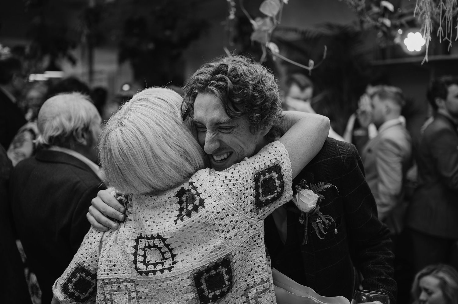 An emotional embrace during a wedding celebration captured in black and white.