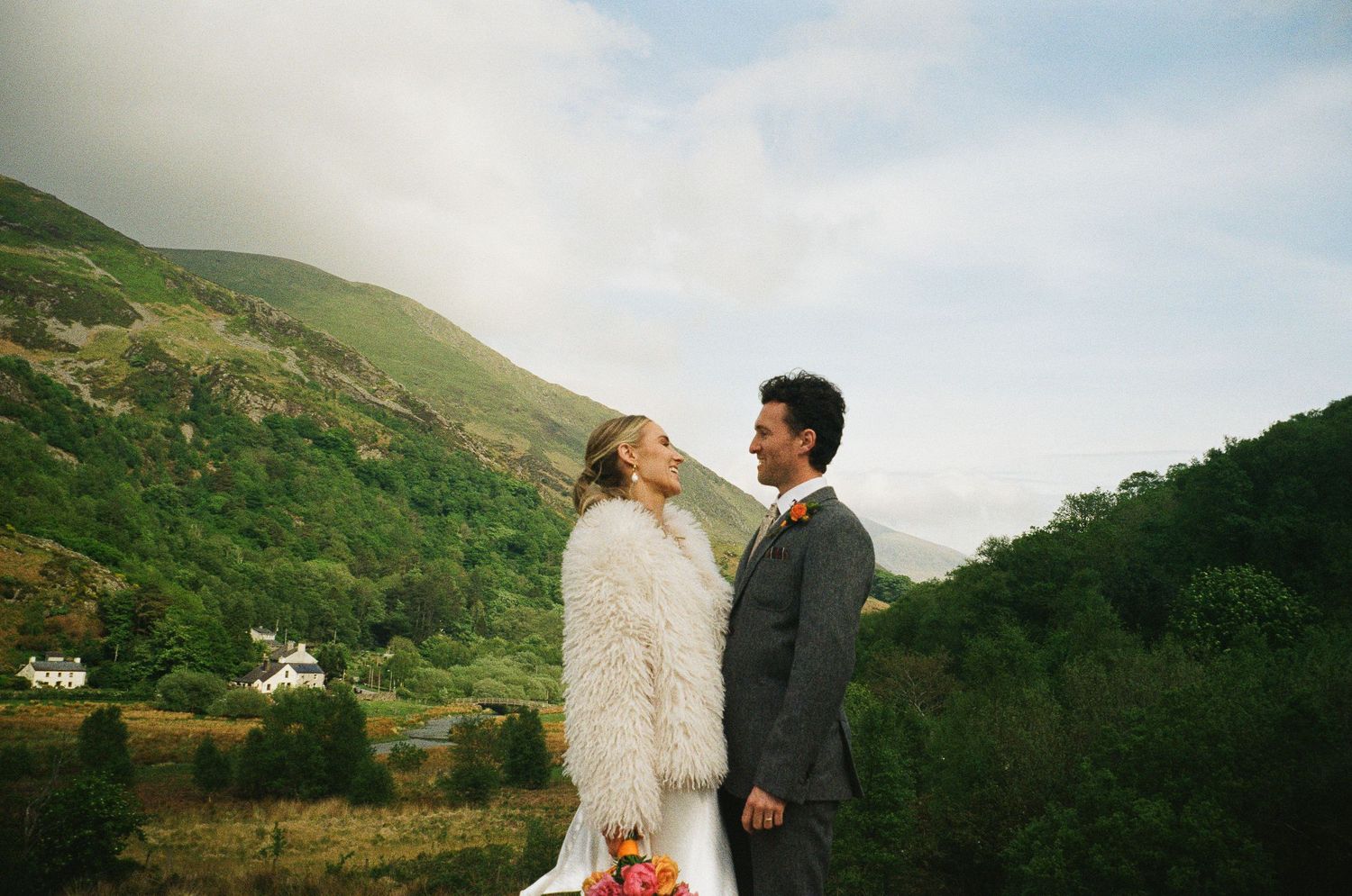 Bride and groom share a romantic moment on a misty hillside surrounded by lush green mountains on their wedding day.