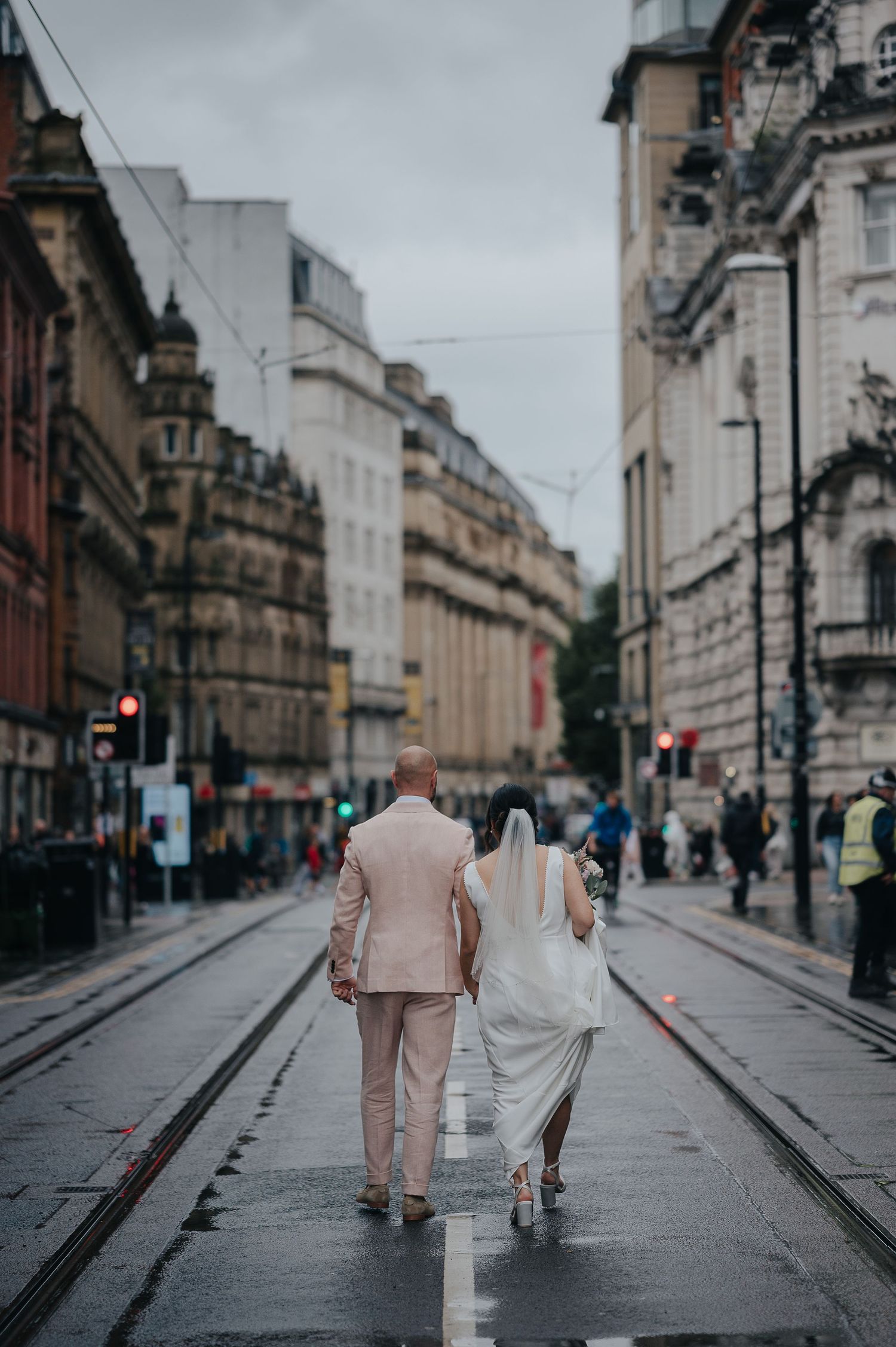 A wedding couple walks down a historic city street with beautiful architecture.