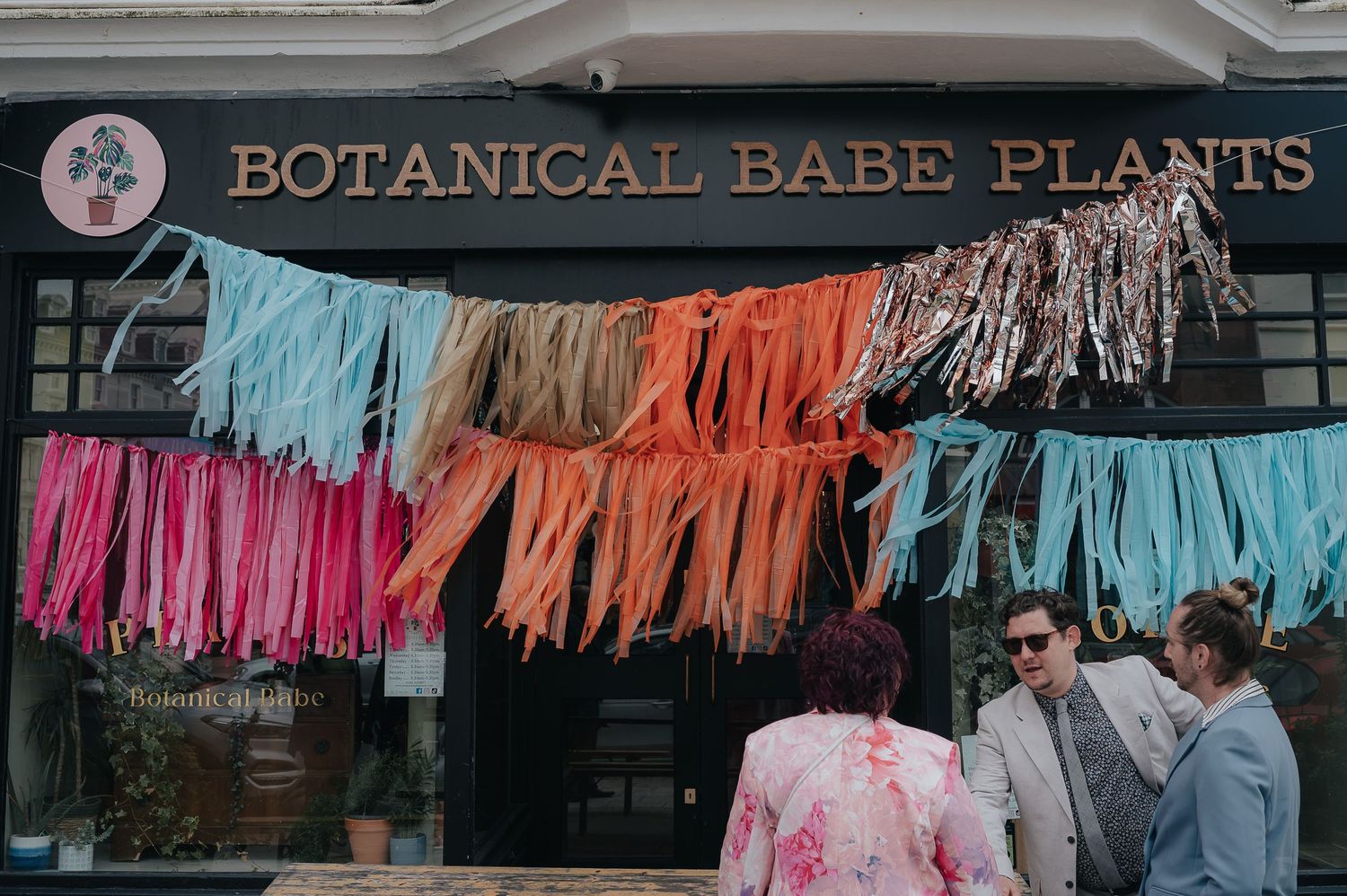 Colorful tissue paper garland hanging outside Botanical Babe Plants storefront.