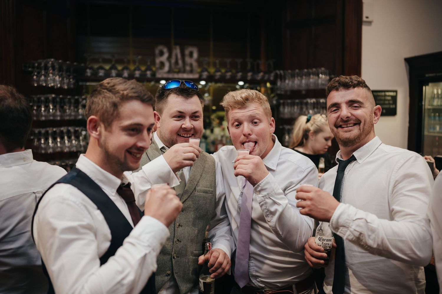 Groomsmen posing playfully at the bar during wedding reception celebrations.