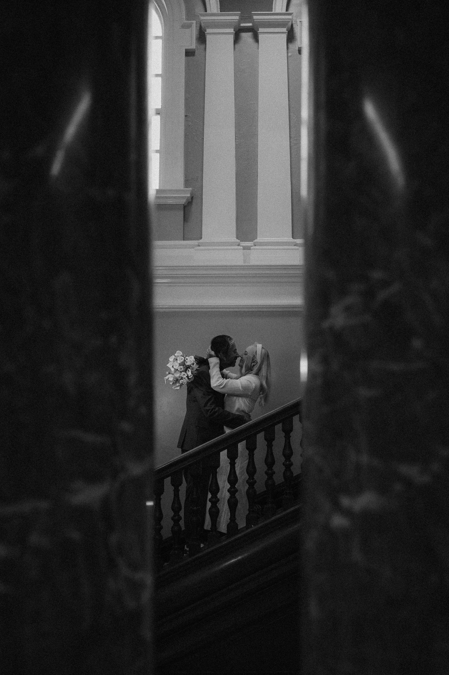 Silhouetted figures walking up a grand staircase in a dimly lit interior.