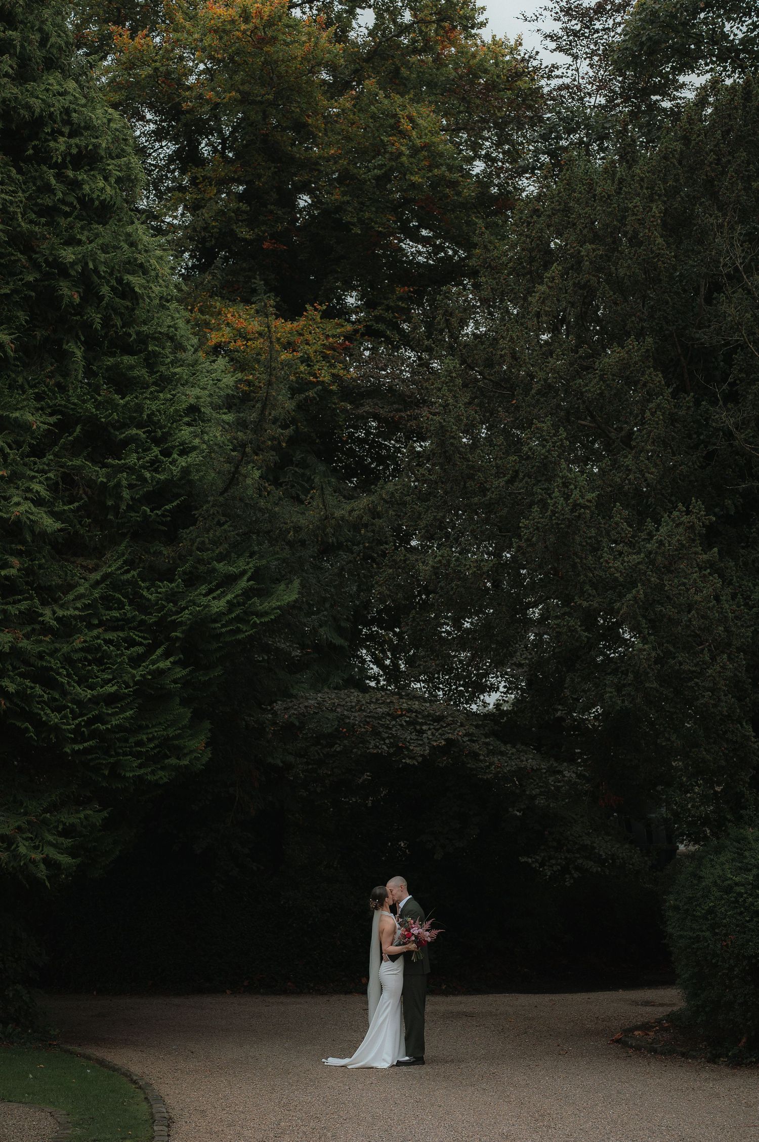 A couple shares an intimate moment in a wooded outdoor setting during a wedding photoshoot.