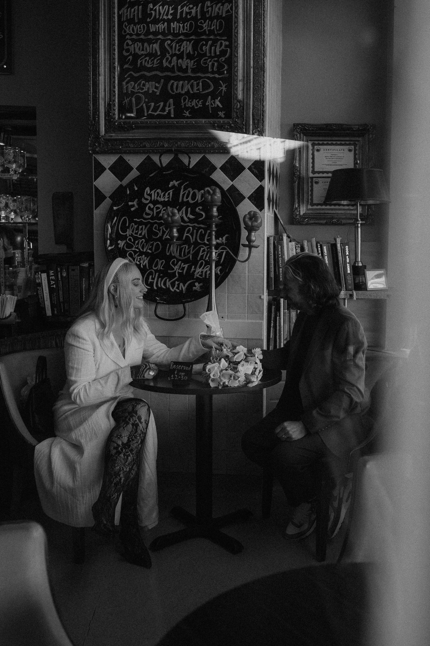 Interior of a cafe with chalkboard menus and seating area in black and white photography.