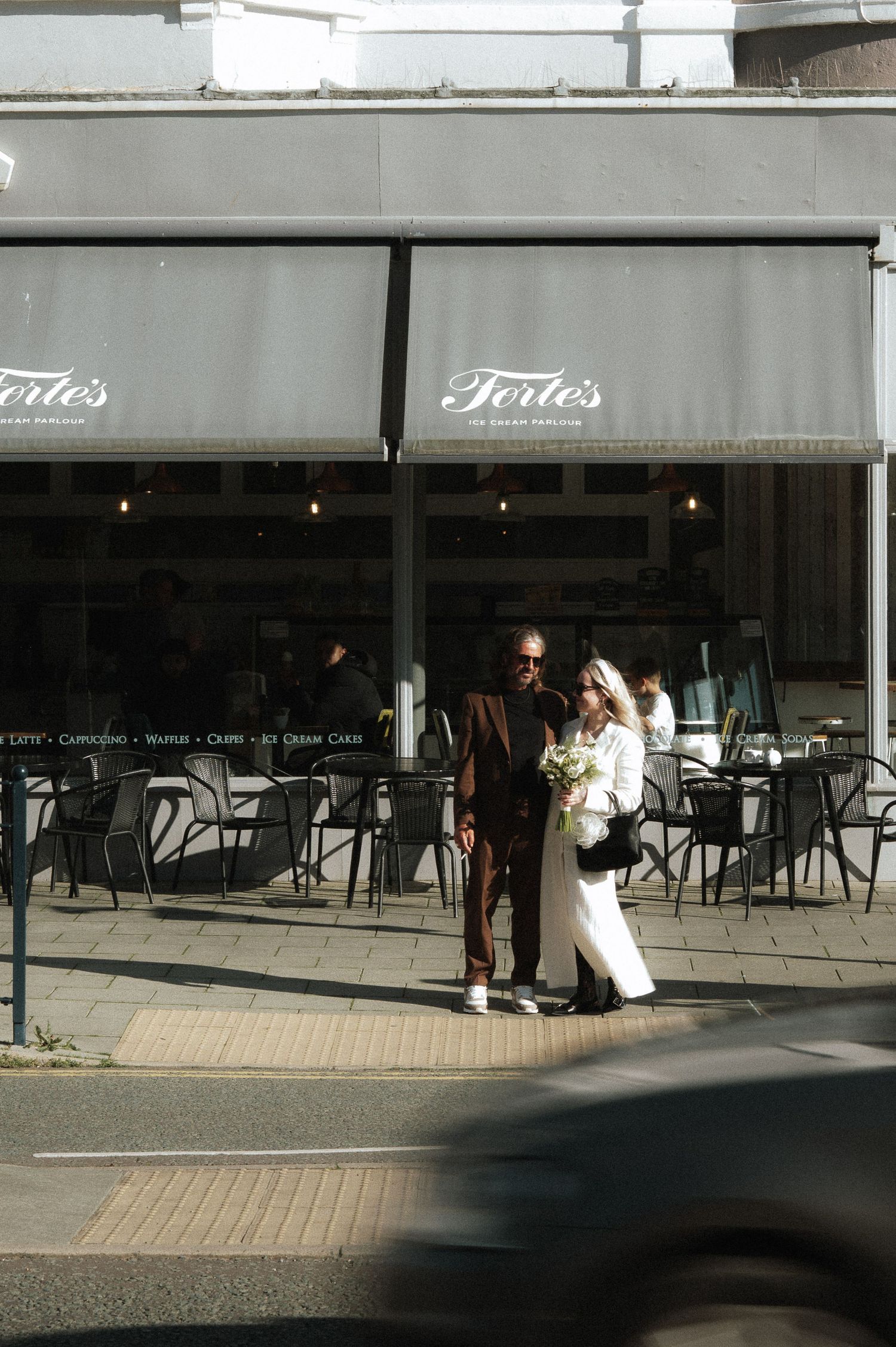 A series of storefront windows showing a cafe or restaurant exterior with dark chairs and tables visible inside.