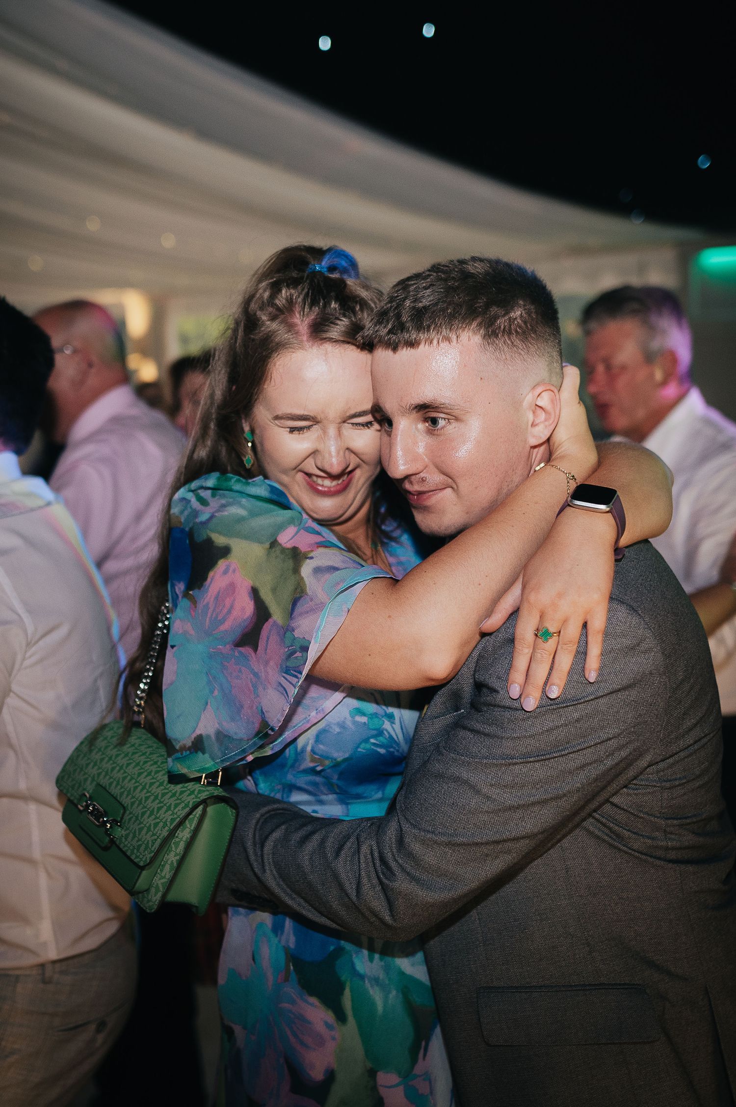 Joyful moment captured on dance floor at wedding reception with party guests in festive attire.
