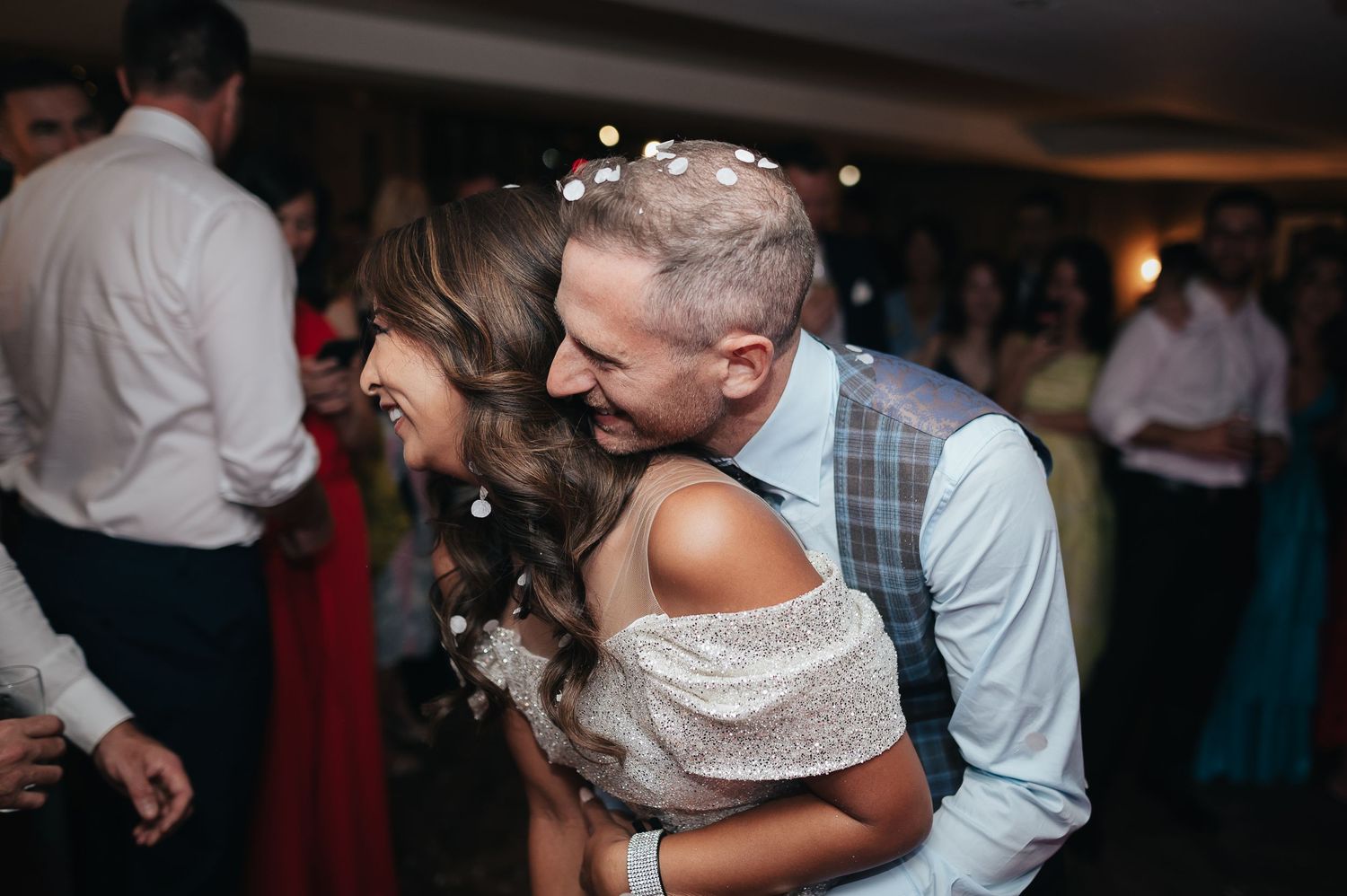 Energetic dancing and laughter captured during wedding reception celebrations.