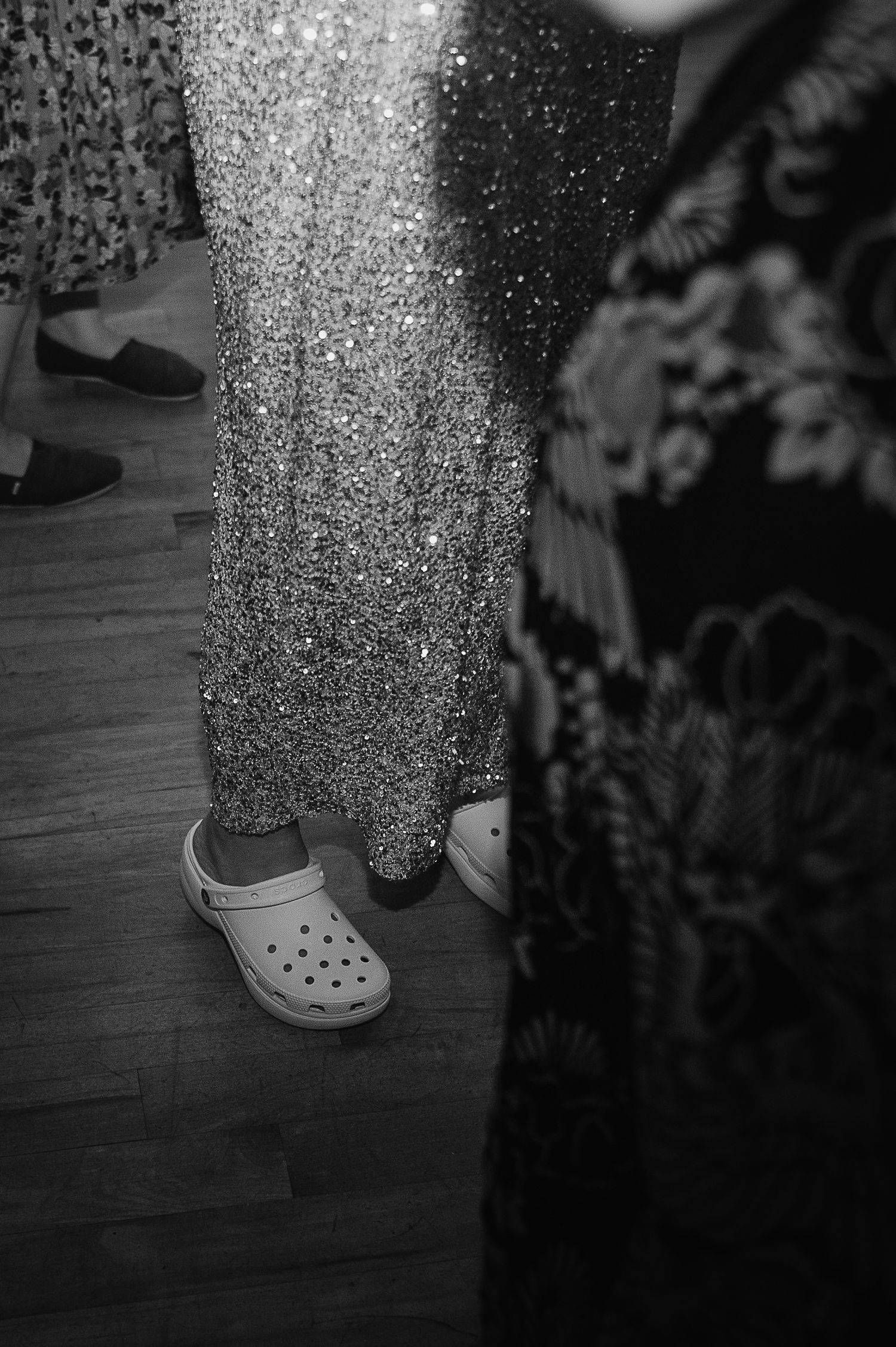 Close-up of someone wearing sparkly formal wear and Crocs at a party.