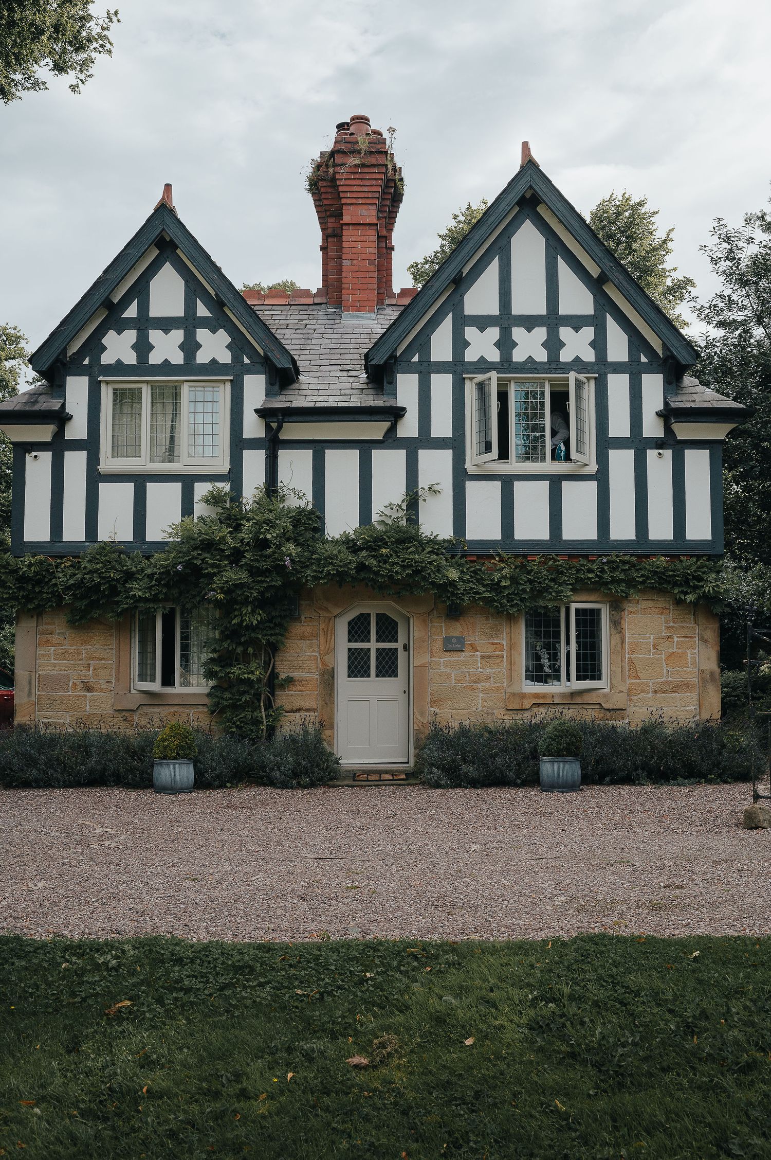 Charming Tudor-style cottage with black and white timber framing and climbing vines on stone walls.