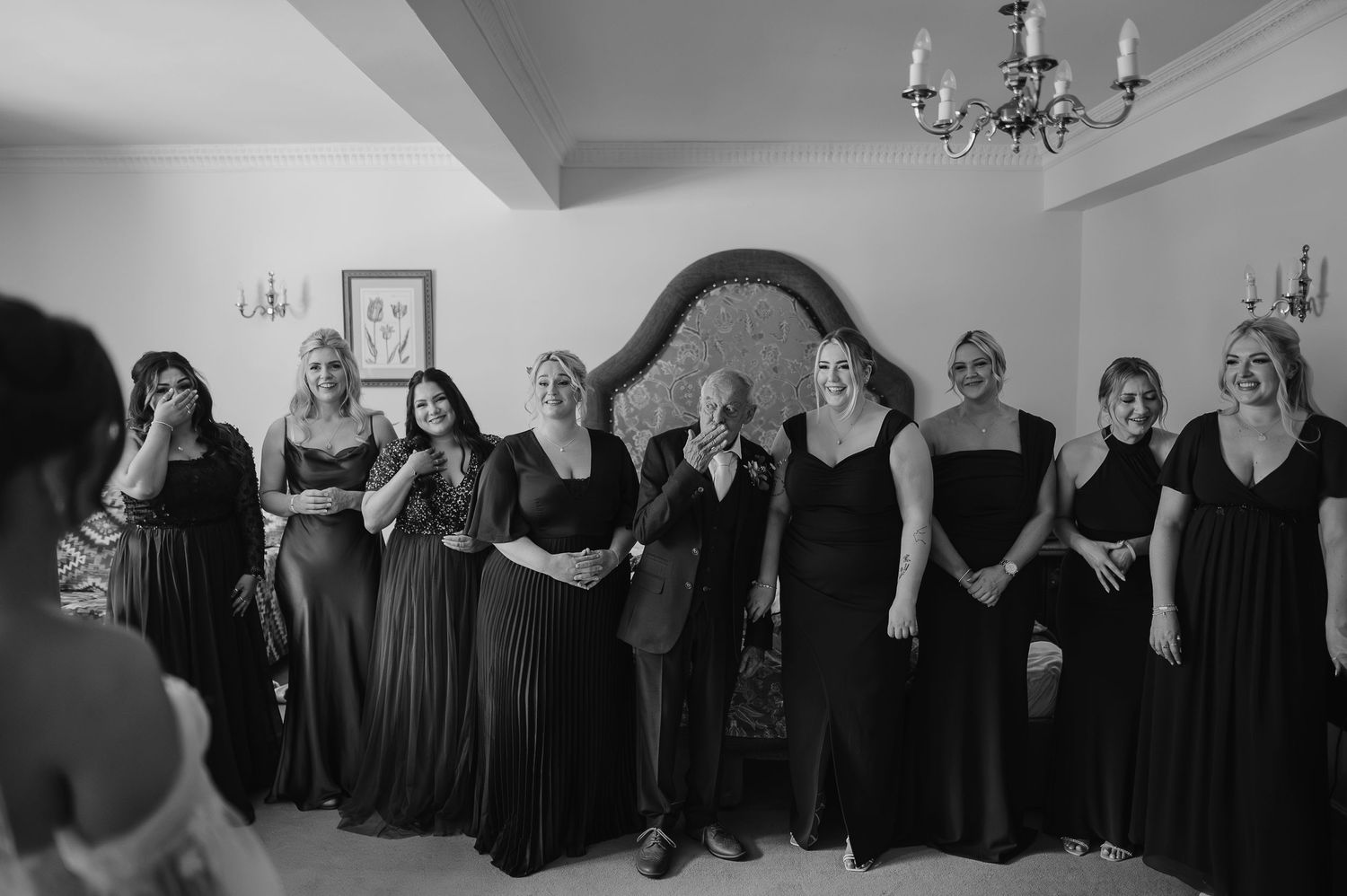 Bridesmaids in elegant black dresses gather for a group photo before the ceremony.