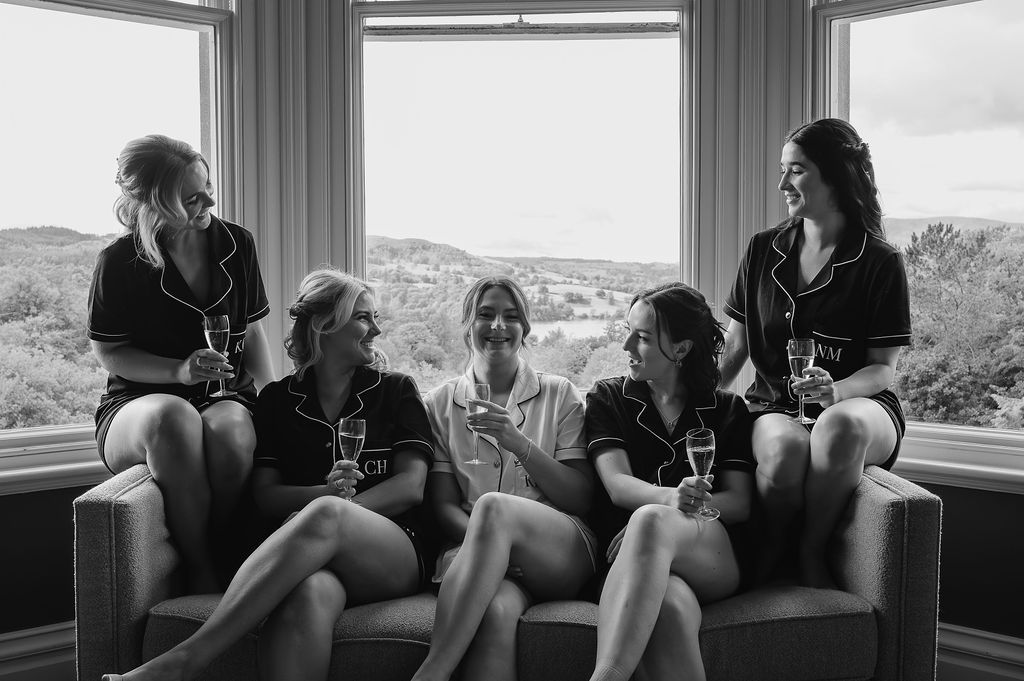 Five women sitting together on a window seat while getting ready for a wedding.