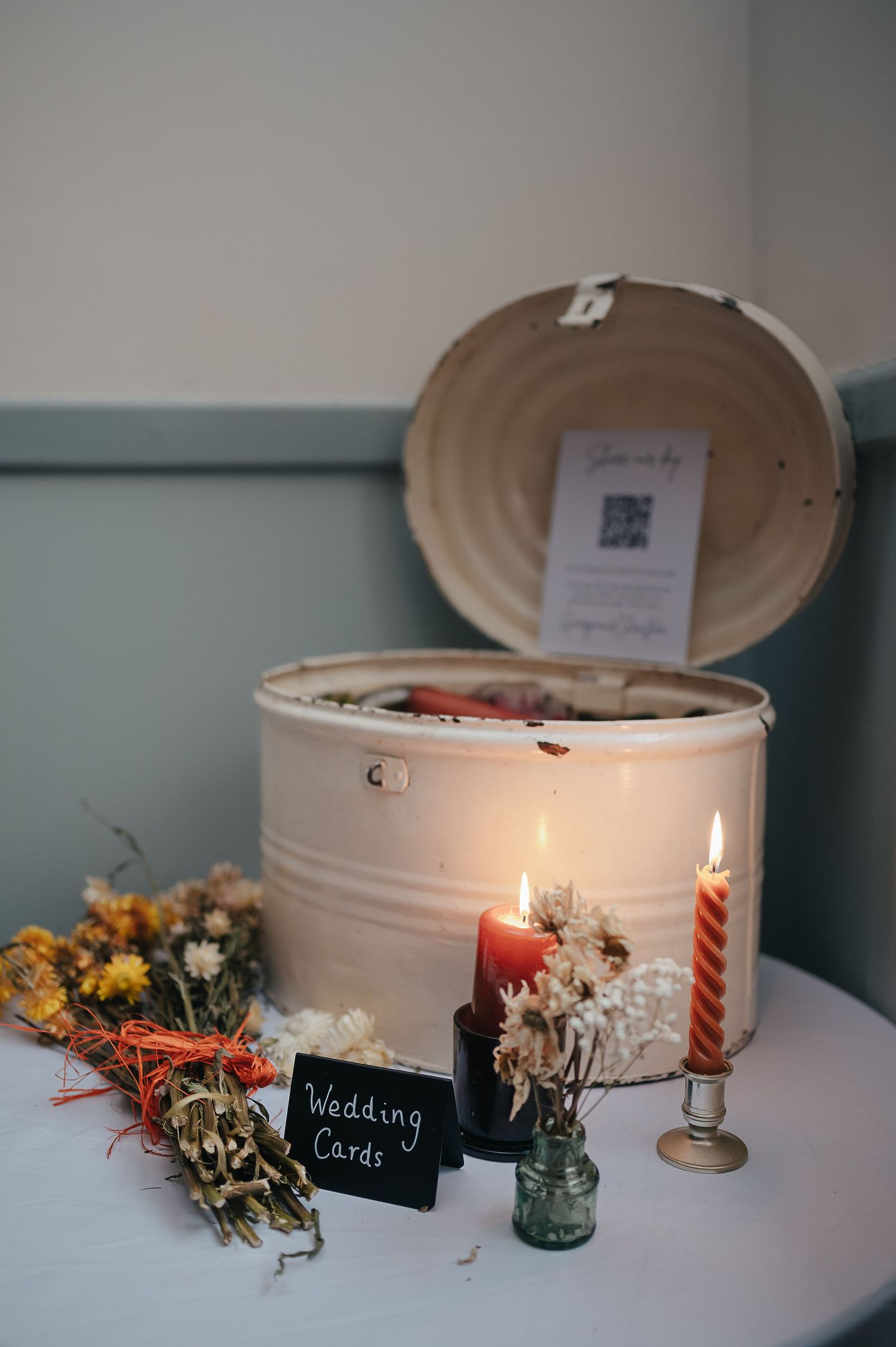 A wedding card box with candles and dried flowers on a white table.