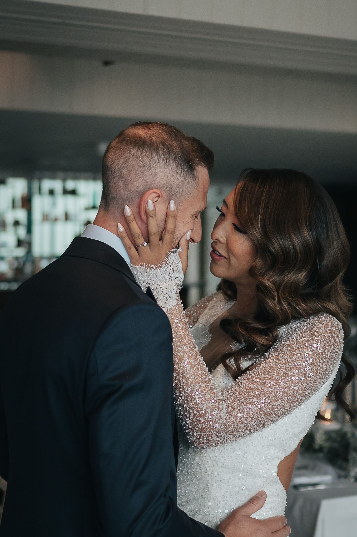 Intimate wedding moment showing couple in sparkly white dress and navy suit sharing tender embrace.