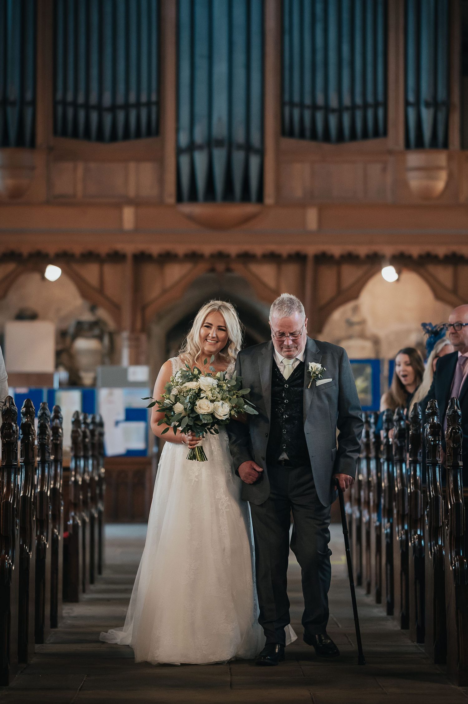 Traditional church ceremony in progress with wooden pews and pipe organ backdrop.