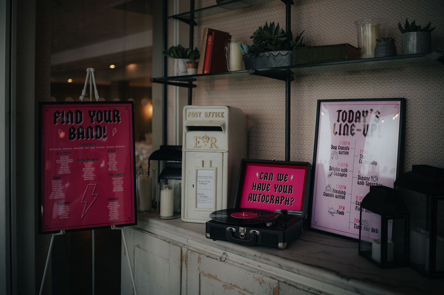 Pink and white menu boards displayed on wooden shelves with decorative items in a cafe interior.