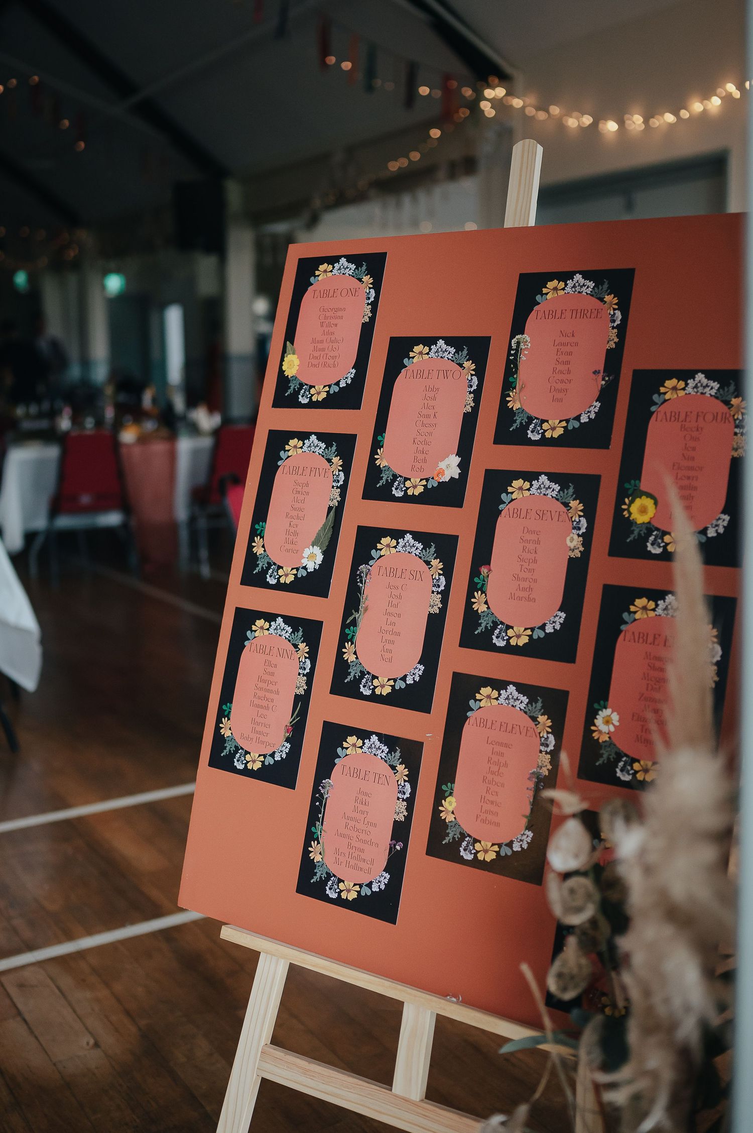 Coral-colored seating chart on an easel with floral decorative frames.