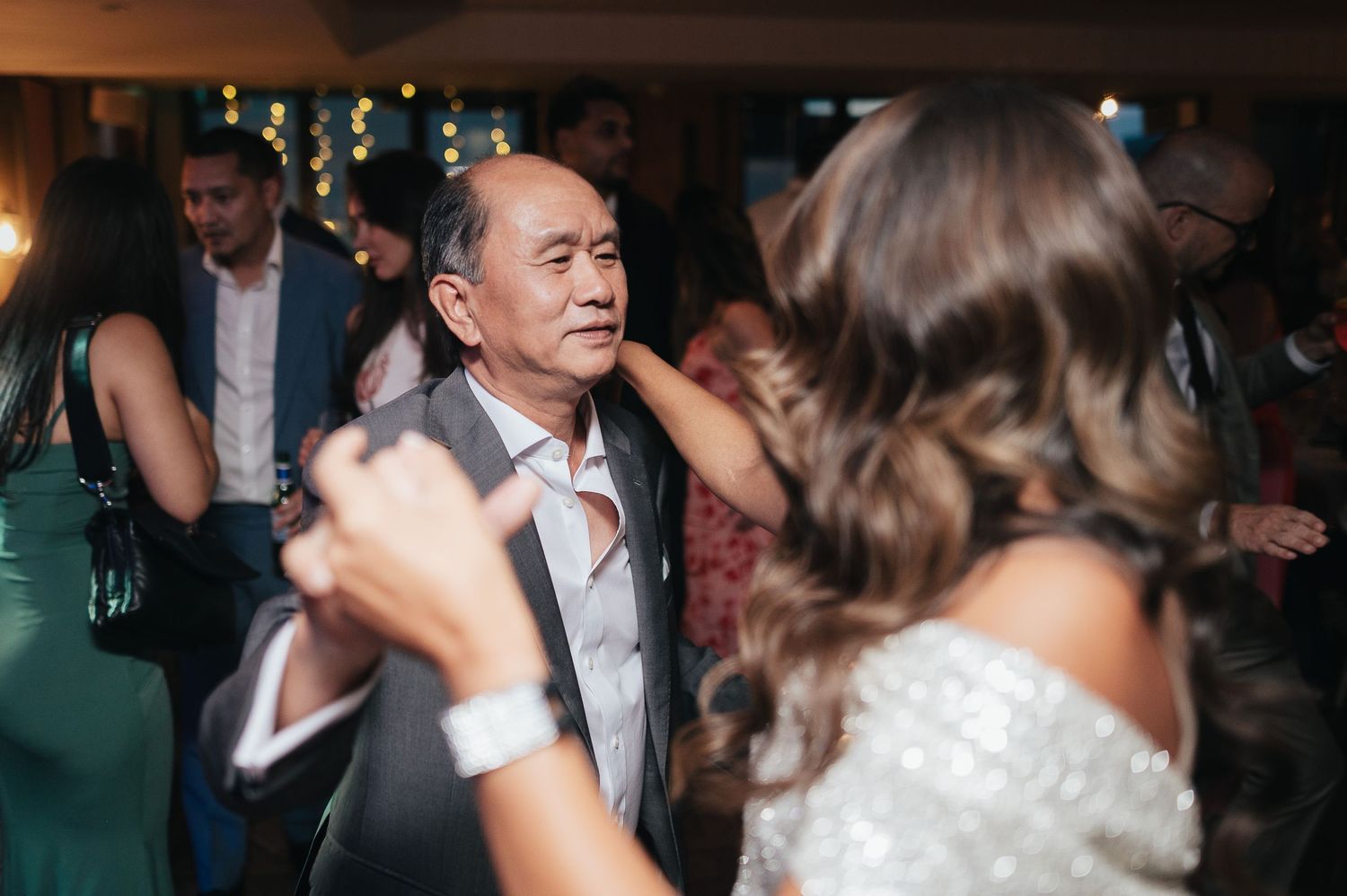 Guests dancing enthusiastically on a dimly lit dance floor at an evening celebration.