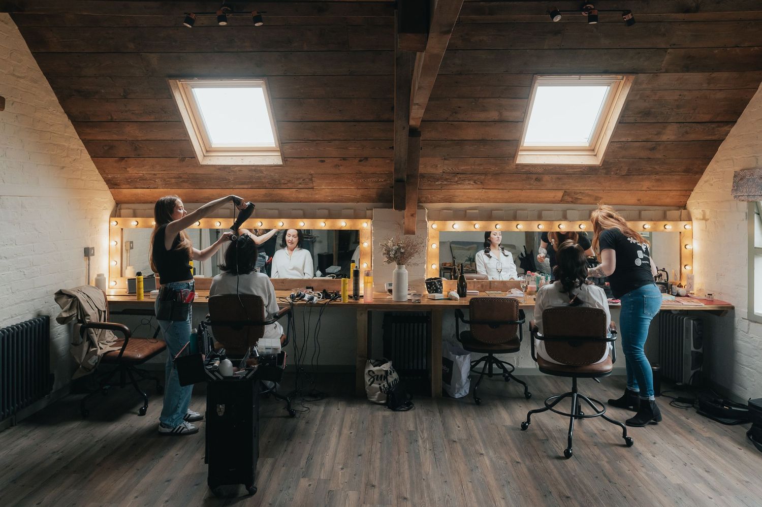 Wedding preparation scene in a rustic room with wooden beams and skylights.