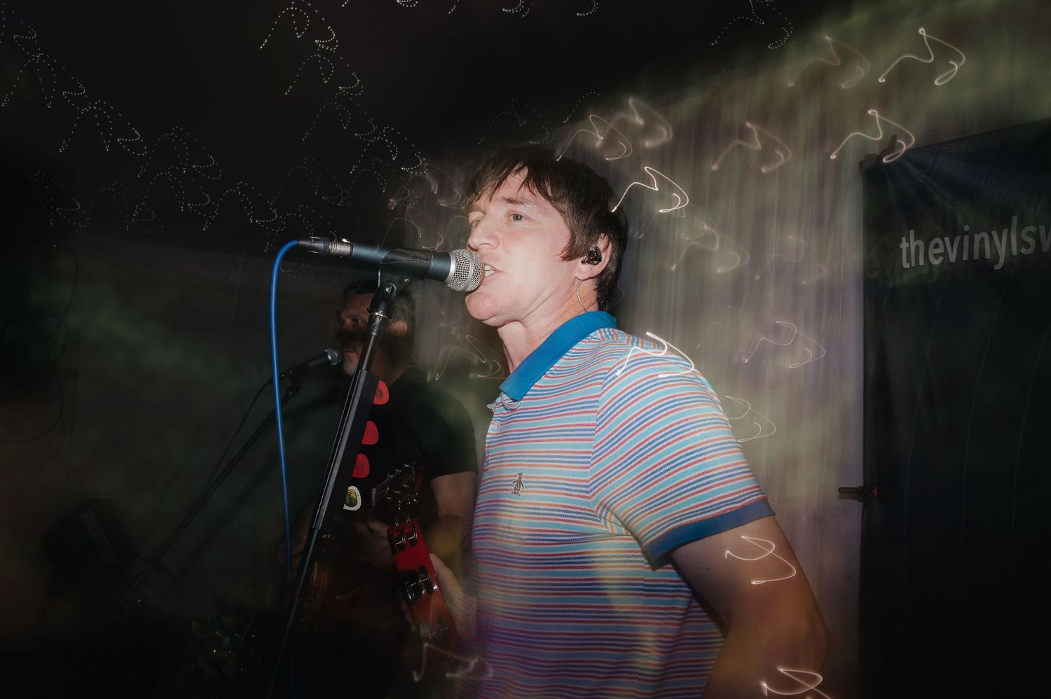 A performer singing passionately into a microphone on a smoke-filled stage.
