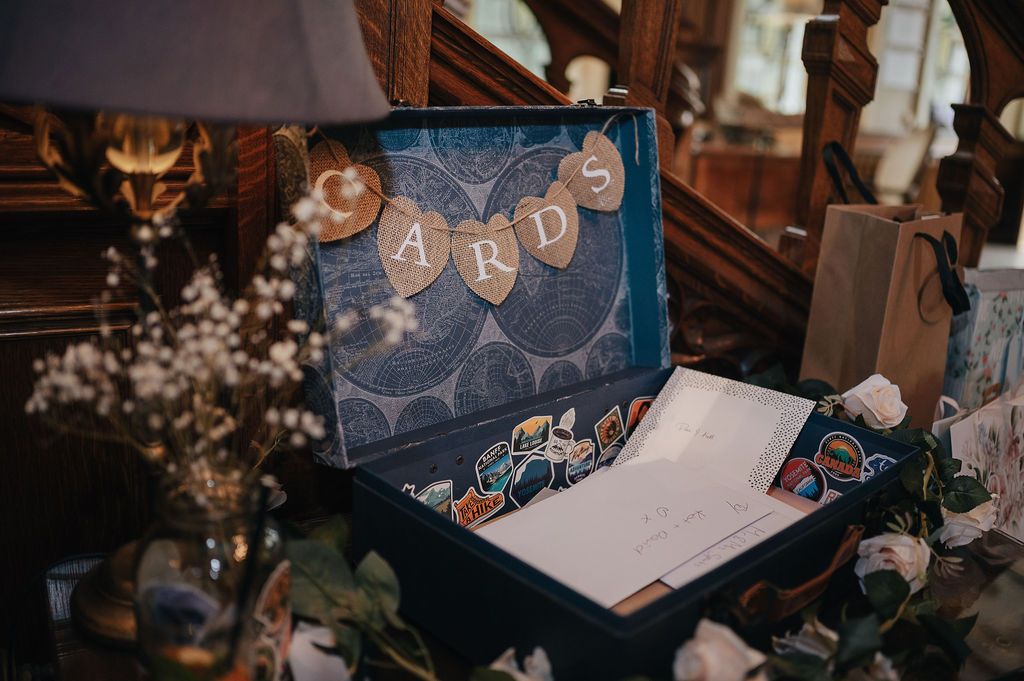 Wedding guestbook display with decorative text and floral arrangements on a wooden table.