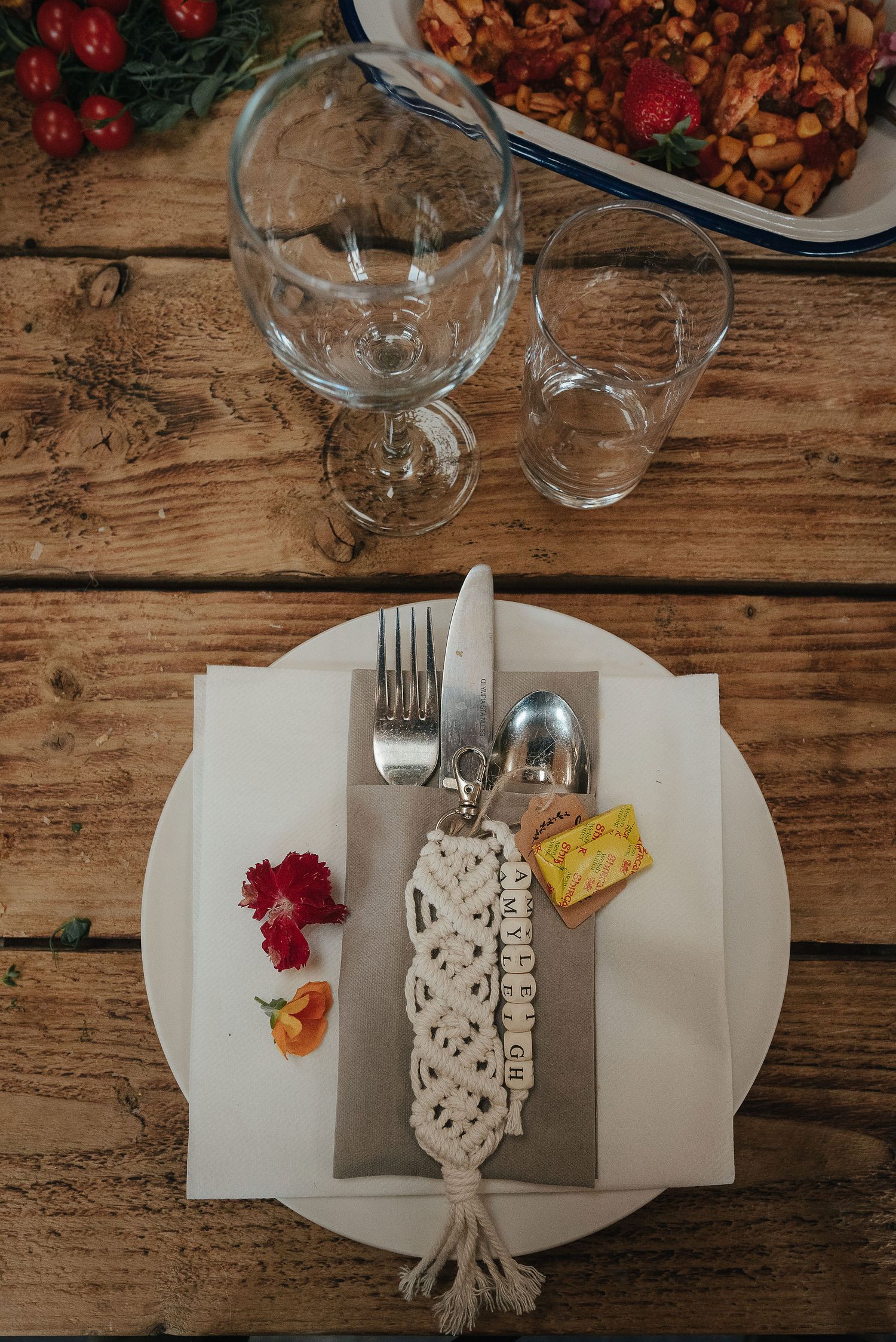 Place setting with white plate, wine glasses, and decorative napkin on rustic wooden table.