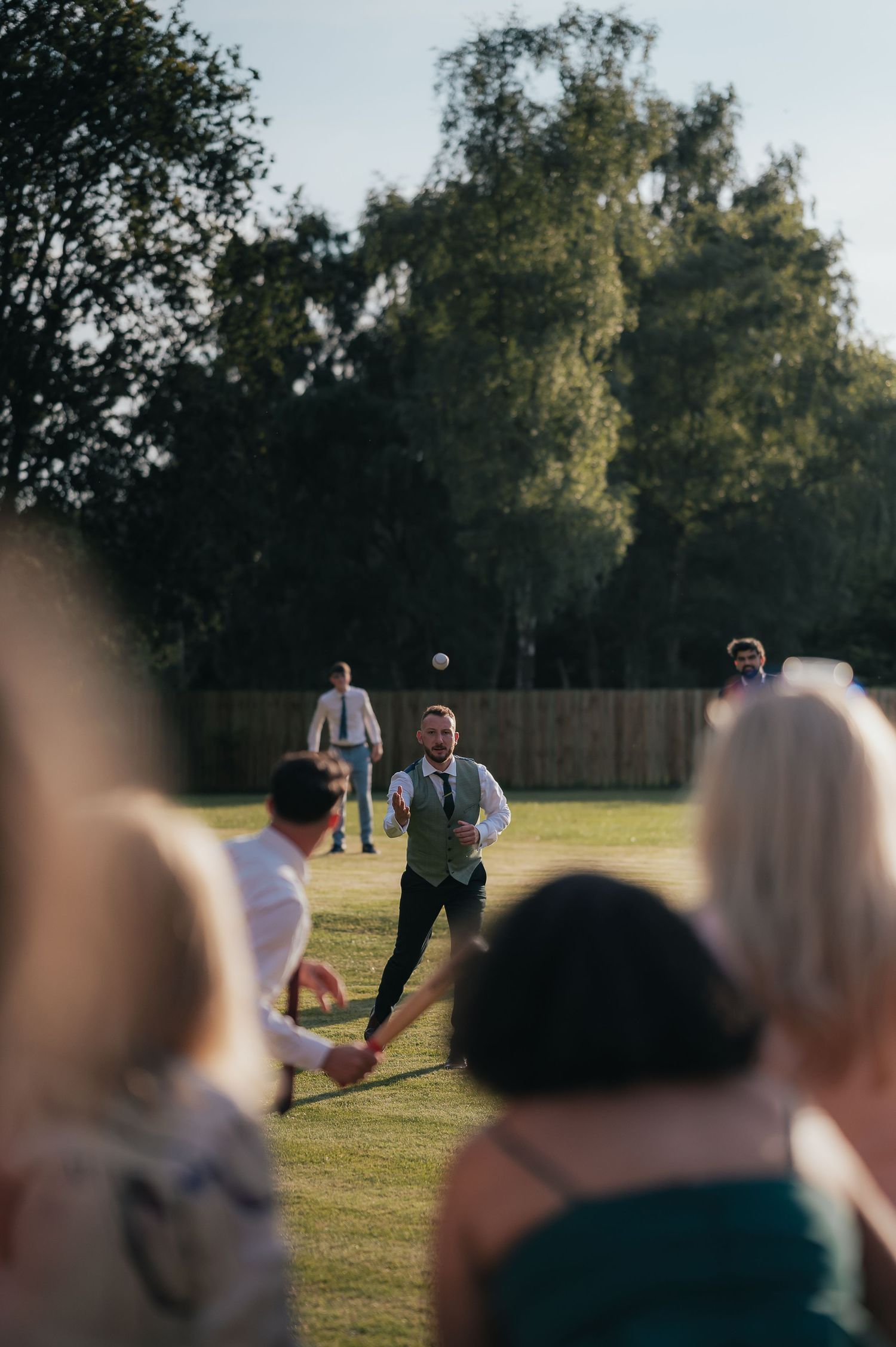 Wedding party guests play lawn games at an outdoor reception.