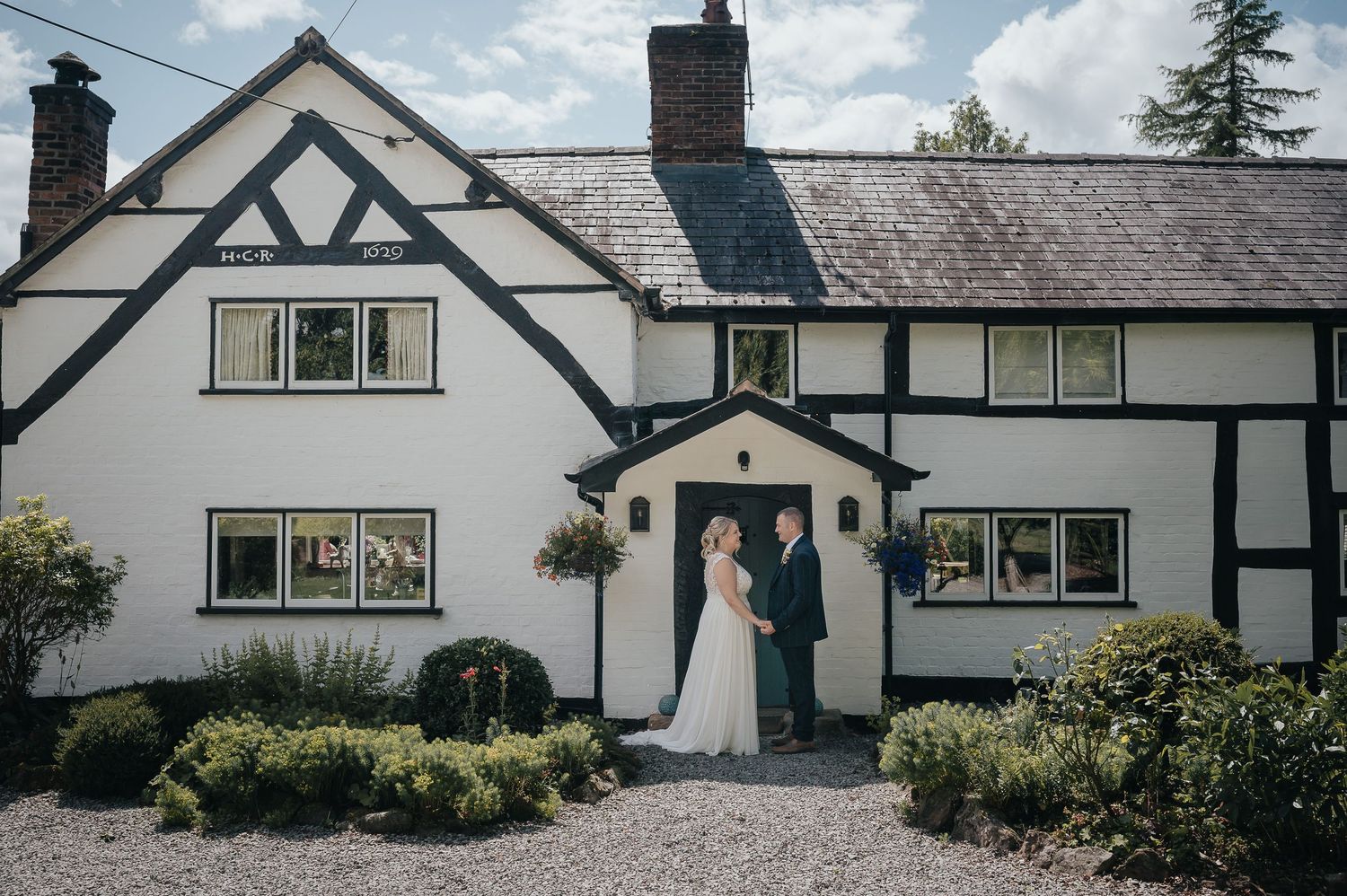 Couple poses in front of charming black and white Tudor-style country house.