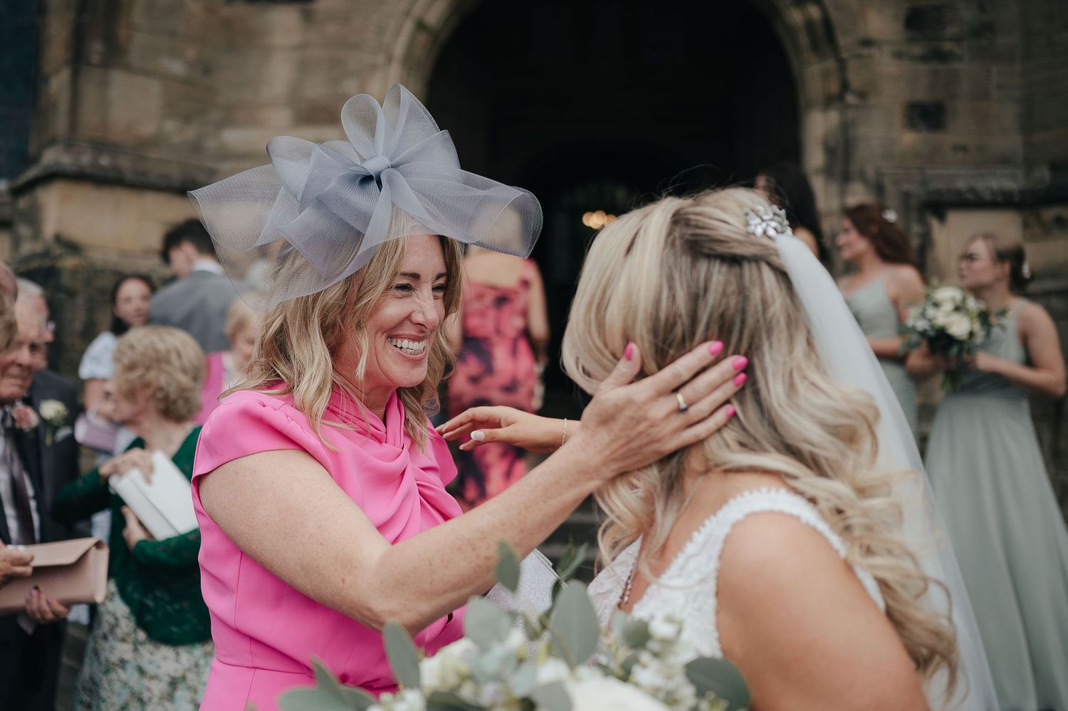 An emotional moment shared between the bride and a guest outside a historic church.