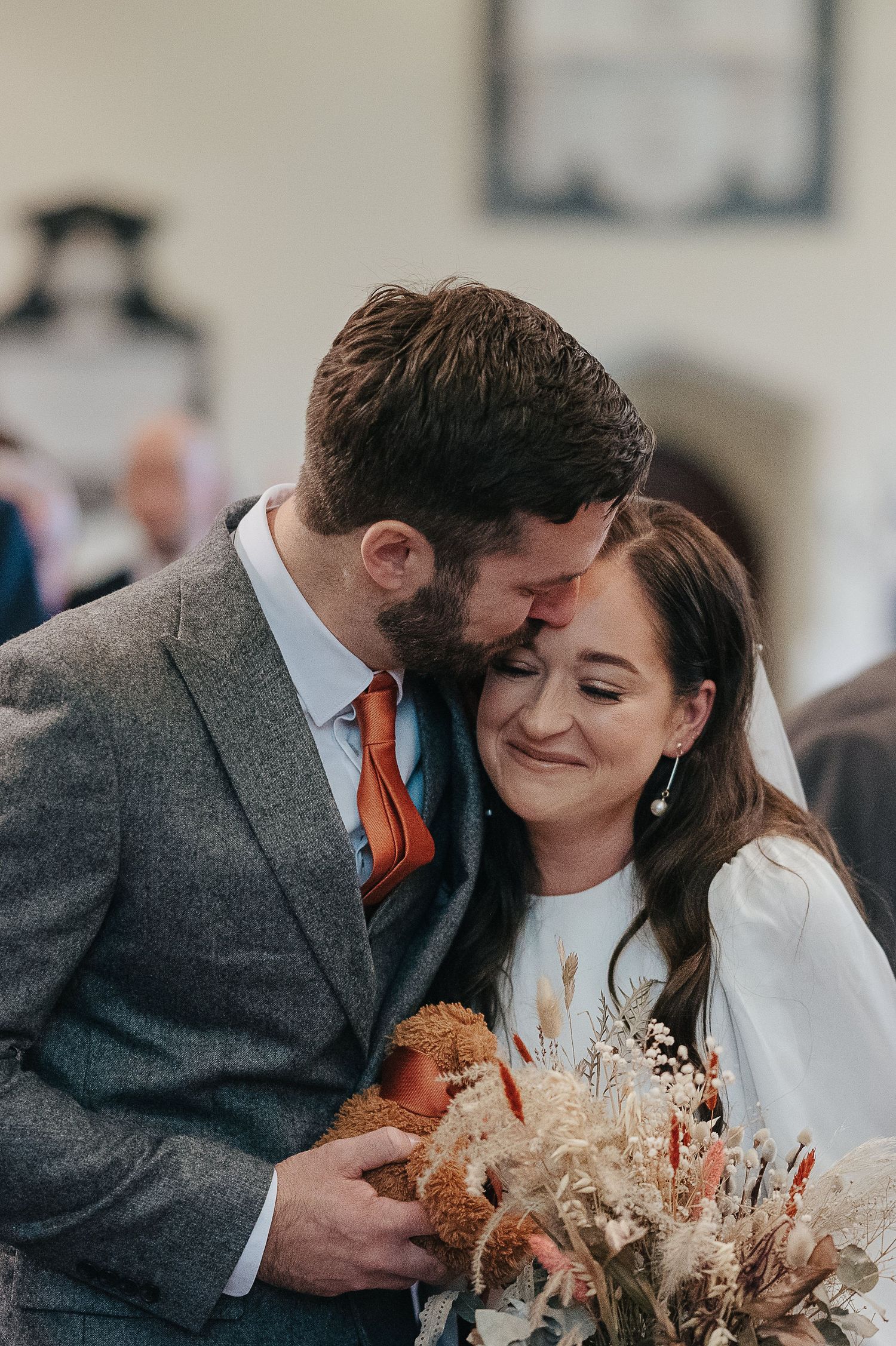 Intimate moment between newlyweds holding a dried flower bouquet.