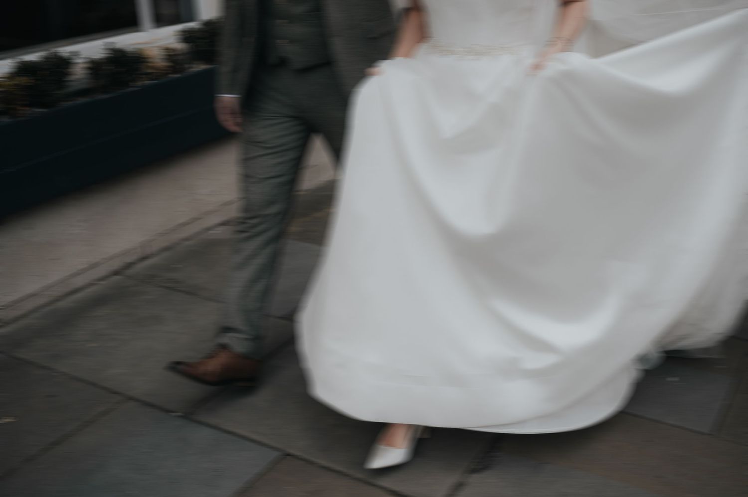 A motion blur capture of wedding dress fabric flowing while walking on a city street.