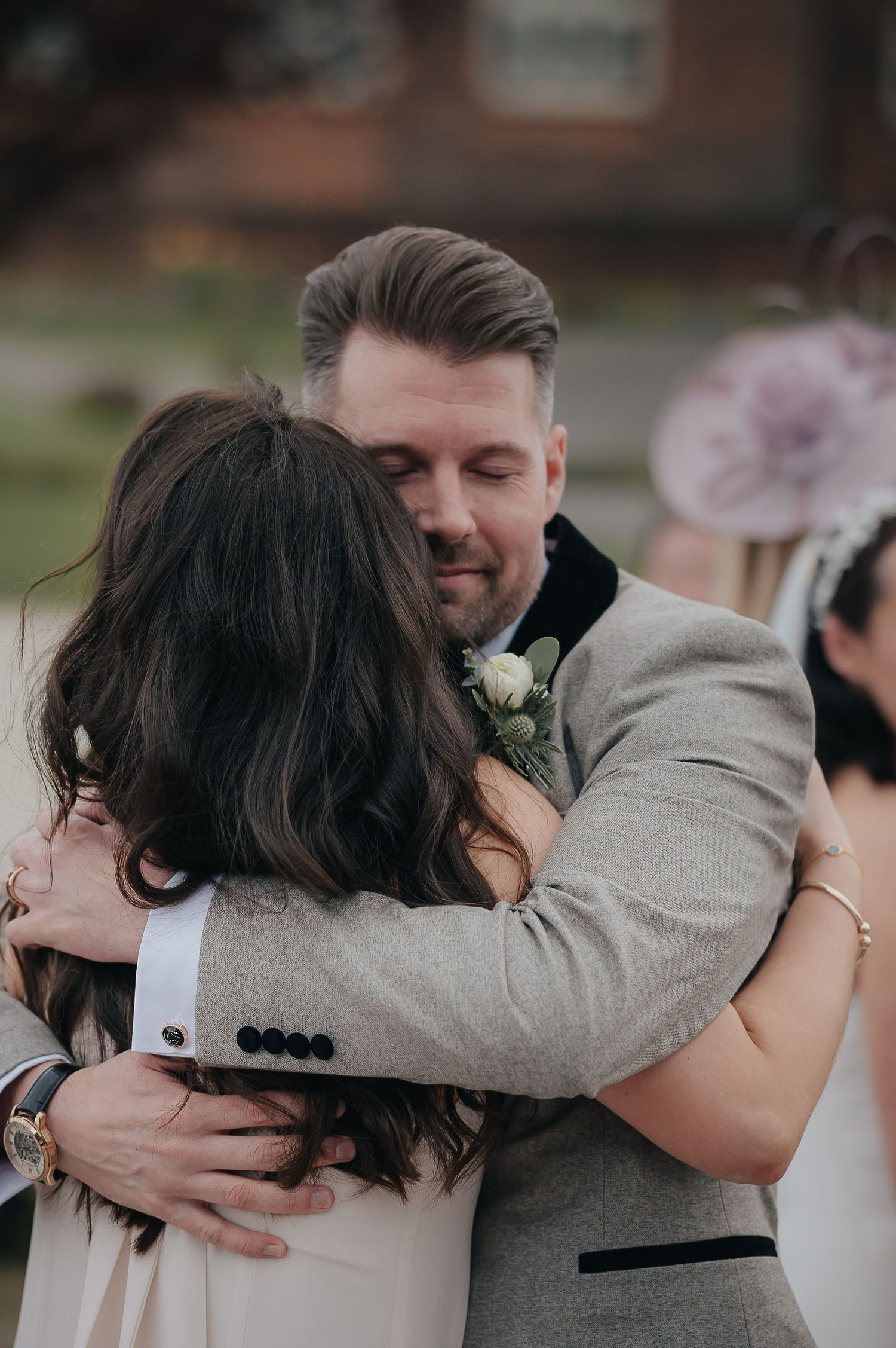 Intimate embrace between wedding guests during outdoor celebration.