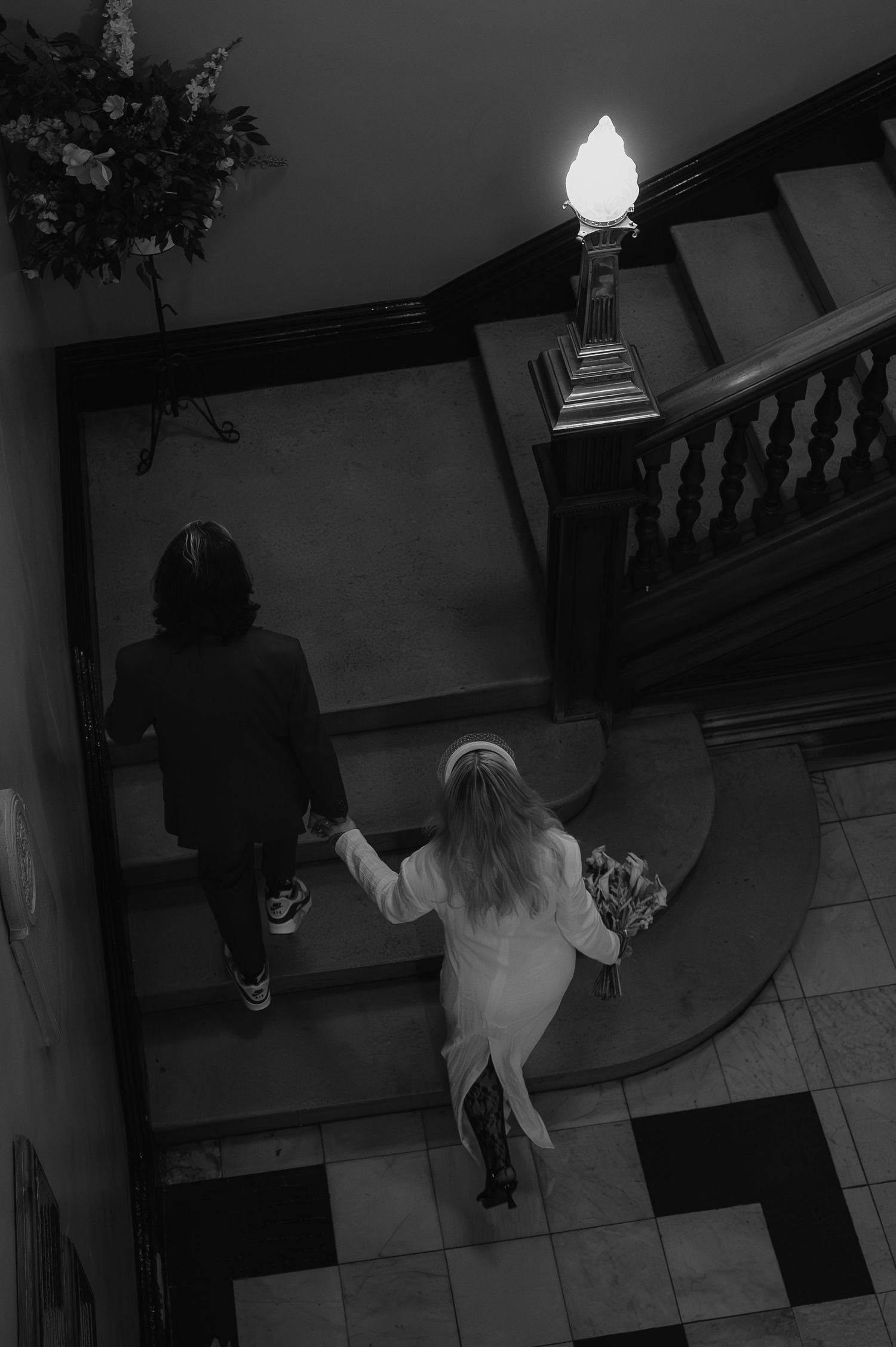 Wedding couple descending grand staircase in dramatic black and white photography.