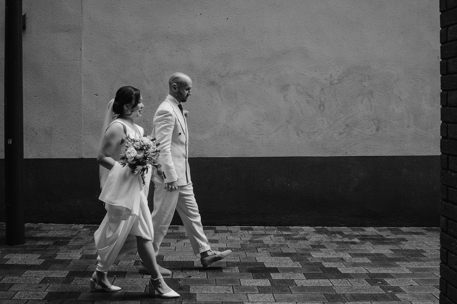Black and white photo of couple walking together on patterned floor.