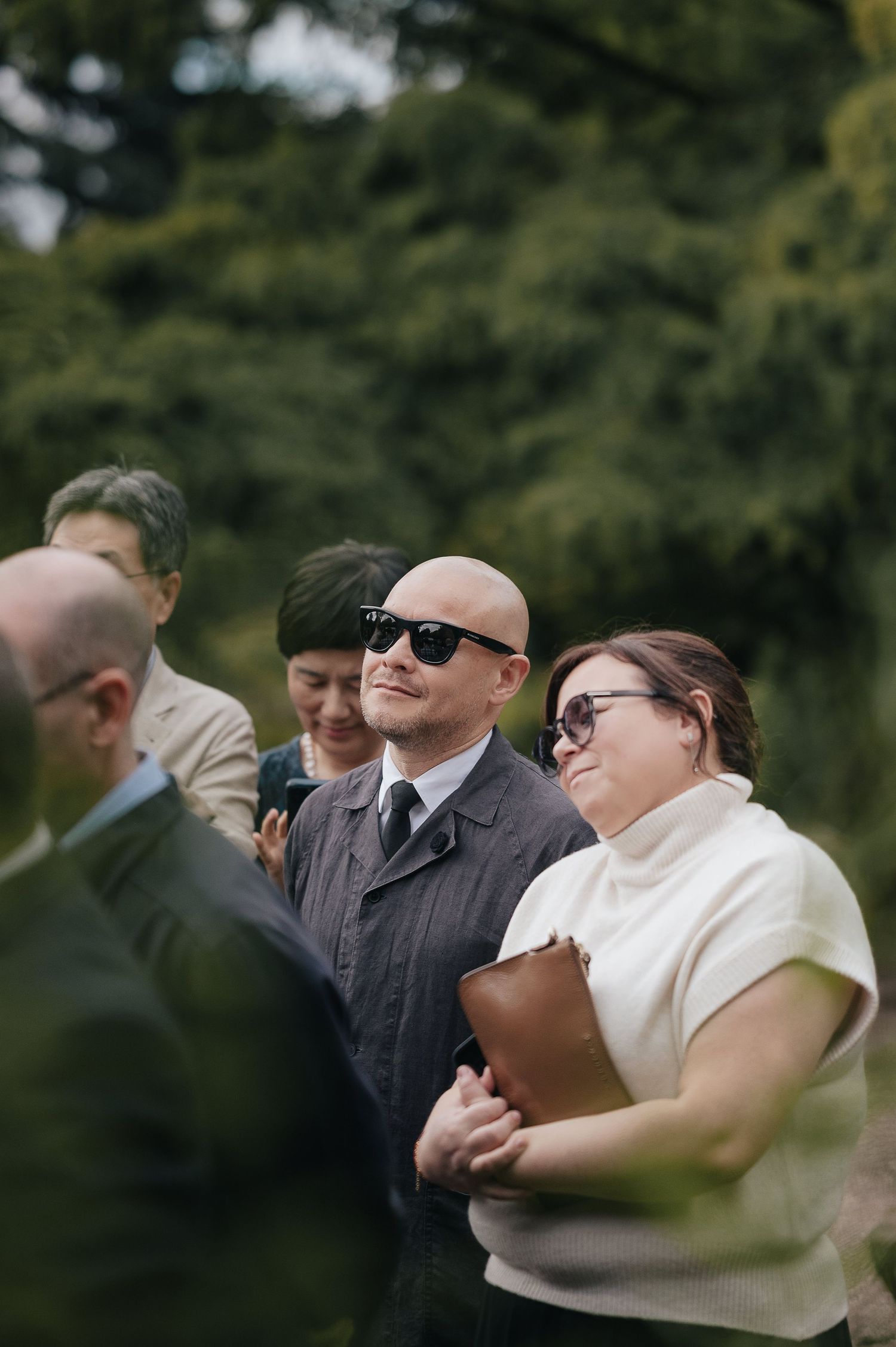 Wedding guests smile and gather outdoors during a casual moment at the ceremony.