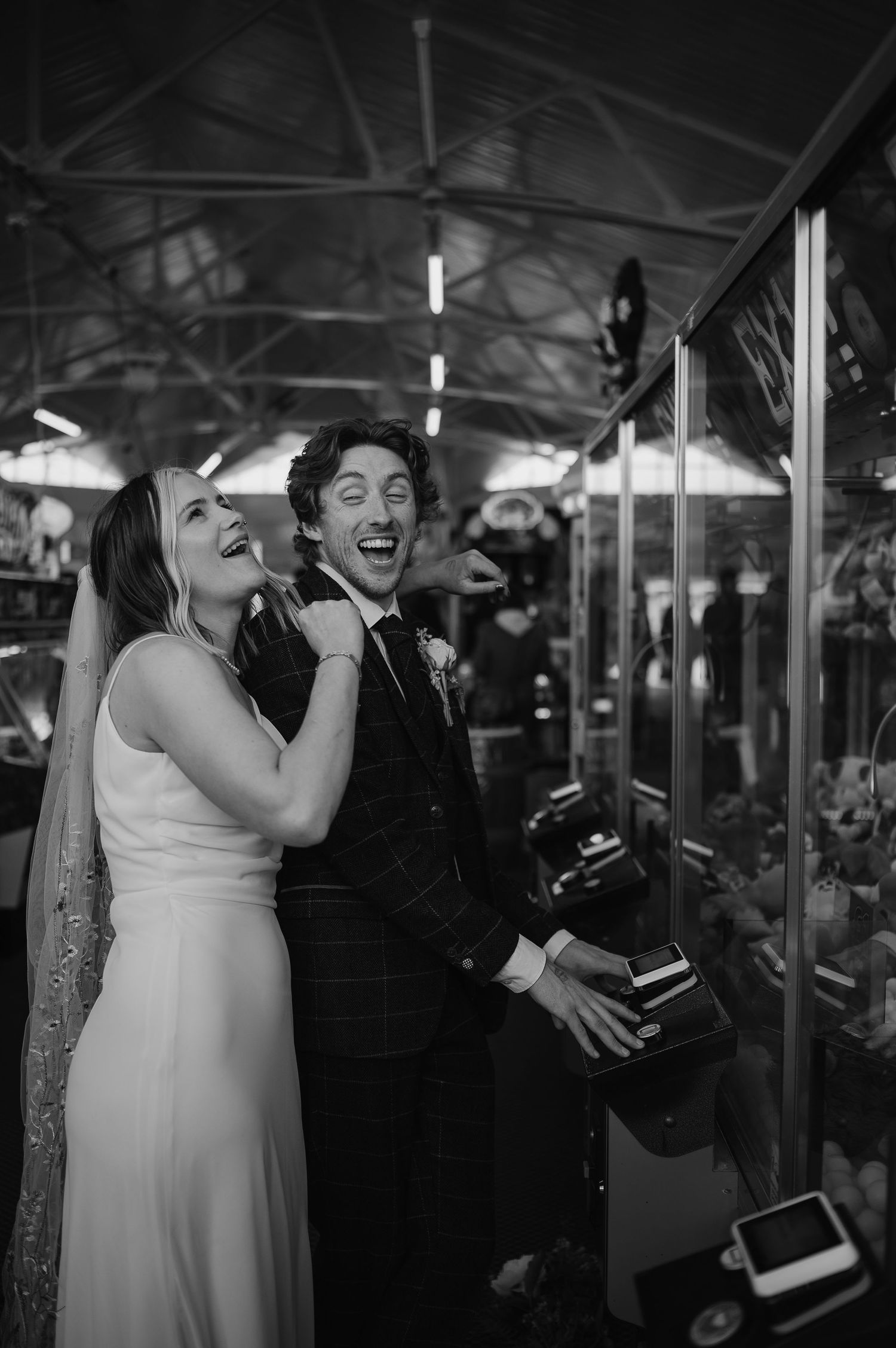 A joyful couple laughs together during their wedding celebration on a carousel at night.